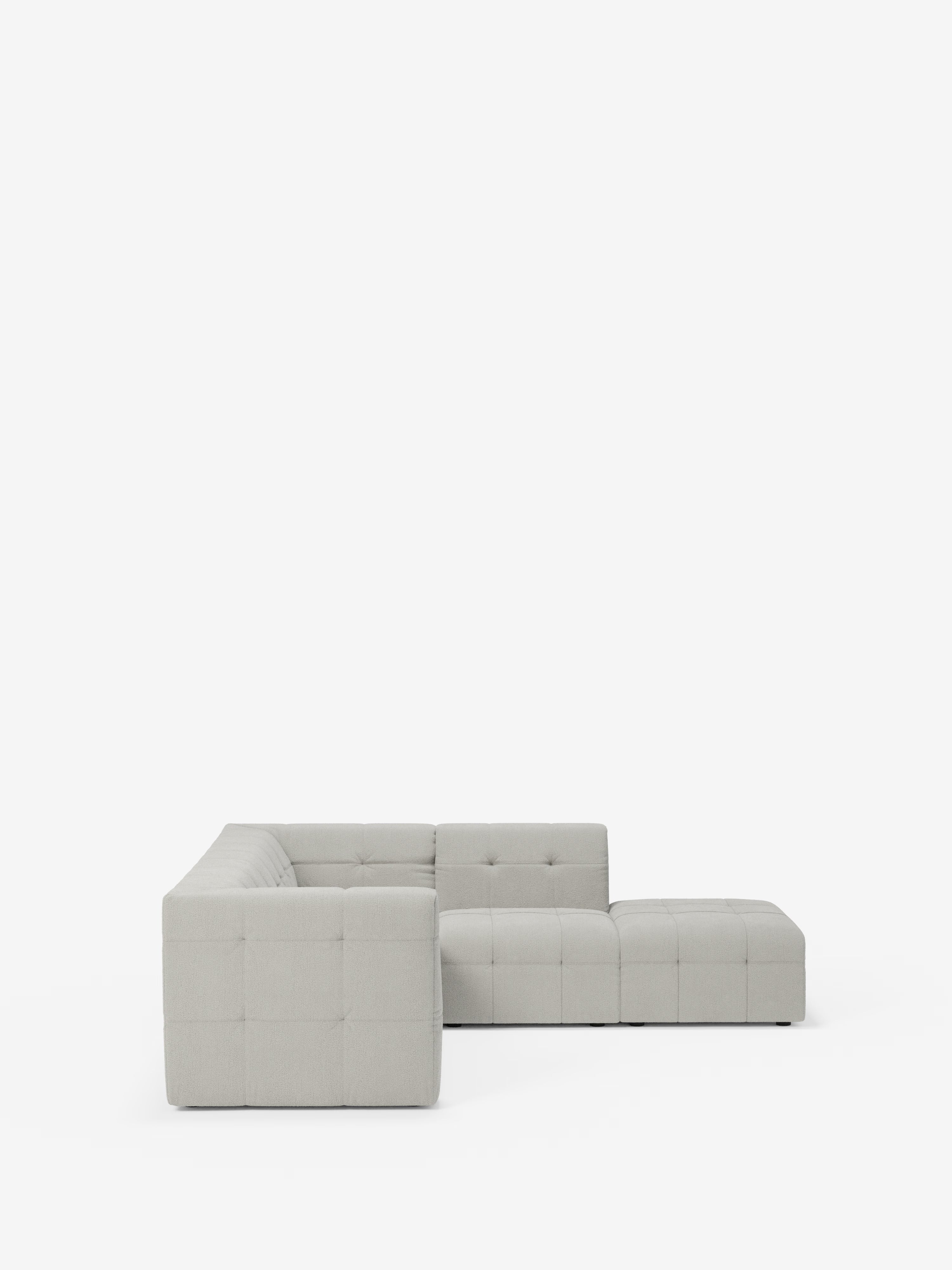 Un divano angolare componibile e modulare Mosaic, moderno e di colore grigio chiaro, realizzato in bouclé da Divani.Store, caratterizzato da un profilo ribassato e da un rivestimento capitonné in tessuto T21 antimacchia, è posto su uno sfondo bianco a tinta unita. Questo divano componibile a forma di L comprende una chaise longue con bracciolo sinistro e cuscini di seduta con motivi di cuciture quadrati a griglia.