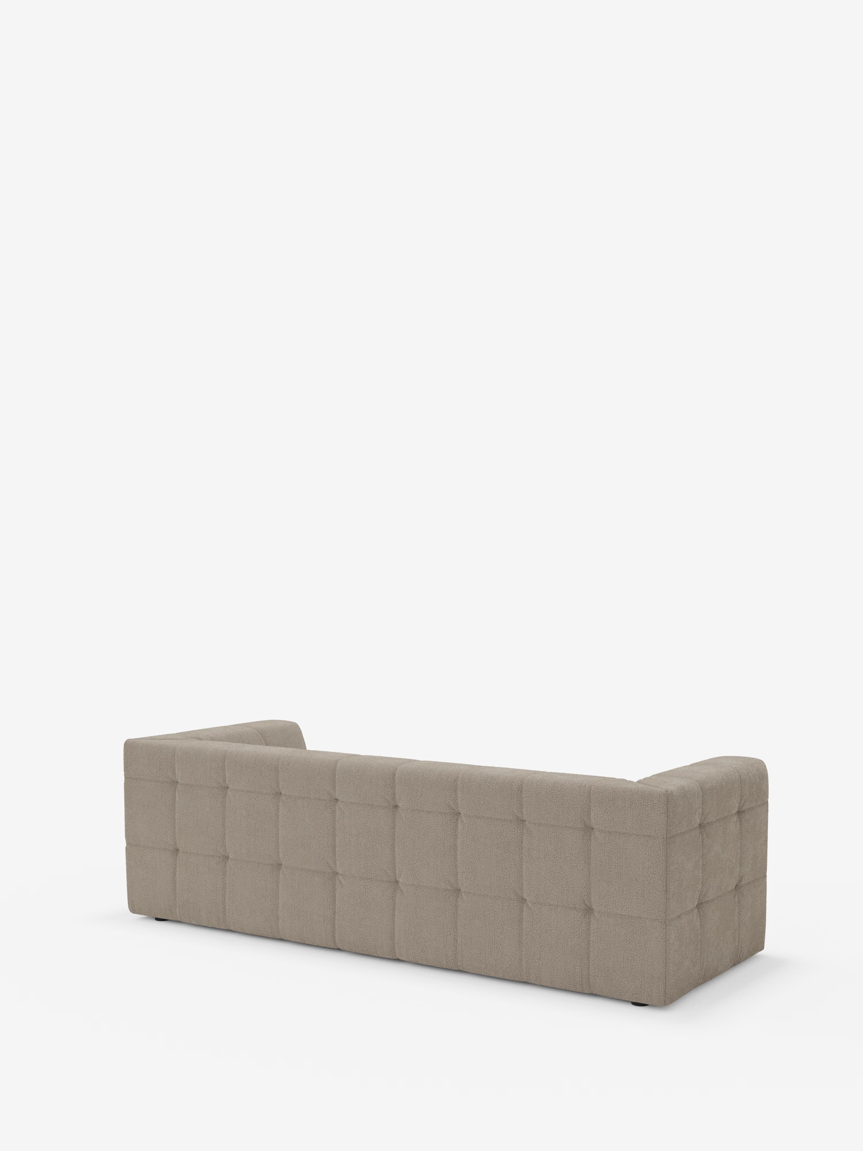 Ecco una frase riscritta che include i dati del prodotto: Il divano modulare Mosaic a 3 e 4 posti in bouclé di Divani.Store presenta una silhouette rettangolare di colore grigio con schienale basso e un motivo trapuntato capitonné lungo lo schienale e i fianchi. Visto da dietro, questo divano moderno presenta tre pannelli trapuntati e braccioli leggermente arrotondati. Sullo sfondo bianco a tinta unita, il tessuto smacchiabile T21 e il design minimalista risaltano in modo particolare.