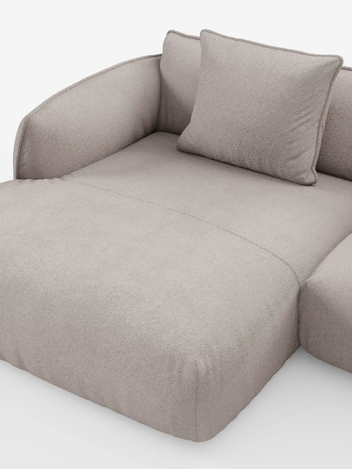 Un divano angolare panoramico componibile Nimbus in stile contemporaneo con penisola e angolo in tessuto smacchiabile T33 di Divani.Store, rivestito in tessuto beige chiaro con una finitura morbida e testurizzata. Questo divano Made in Italy presenta sedute profonde, braccioli arrotondati ed è corredato da un unico cuscino quadrato coordinato, il tutto presentato su uno sfondo bianco a tinta unita.