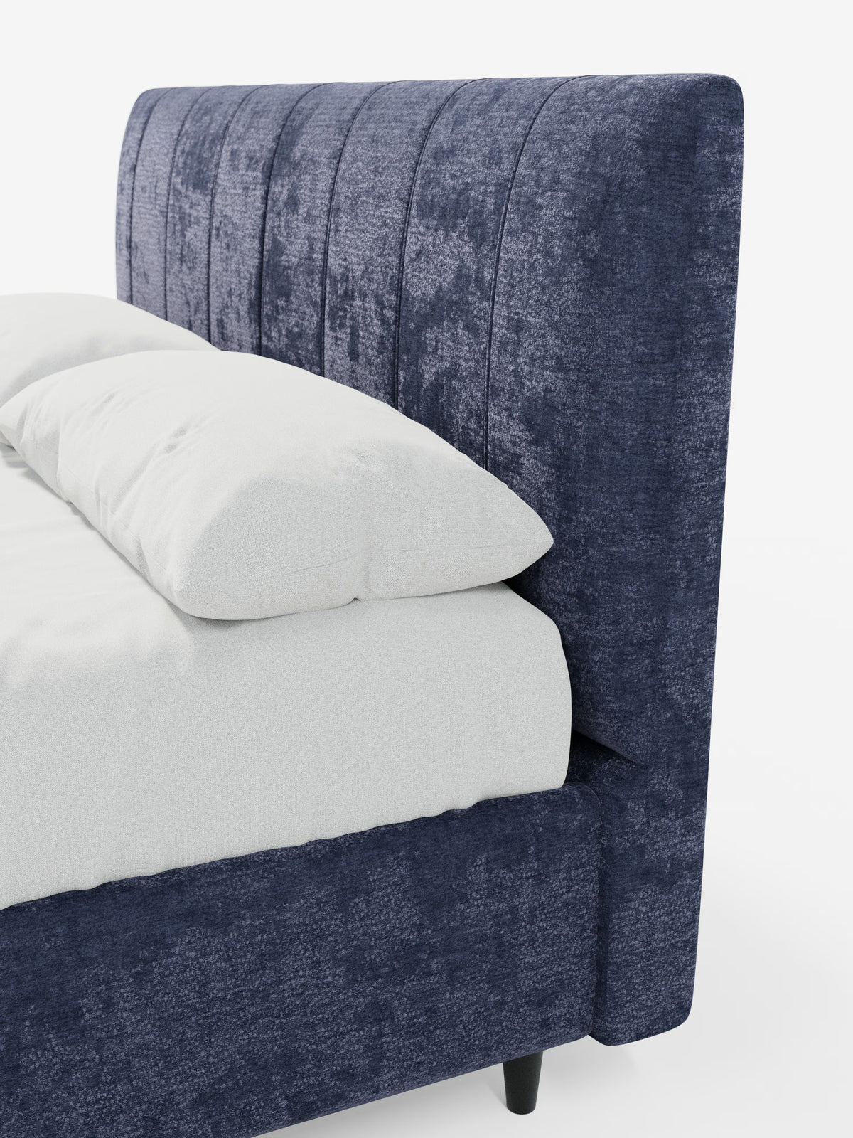Primo piano del letto imbottito con contenitore ONYX di Letti.store, che mette in risalto la sua testiera alta, rivestita con pannelli verticali in tessuto blu navy certificato Oeko-Tex®. Il letto è dotato di biancheria da letto e cuscini bianchi ed è sostenuto da eleganti gambe cilindriche nere. Sullo sfondo bianco, l'immagine mette in risalto il design moderno e raffinato di questo letto contemporaneo.