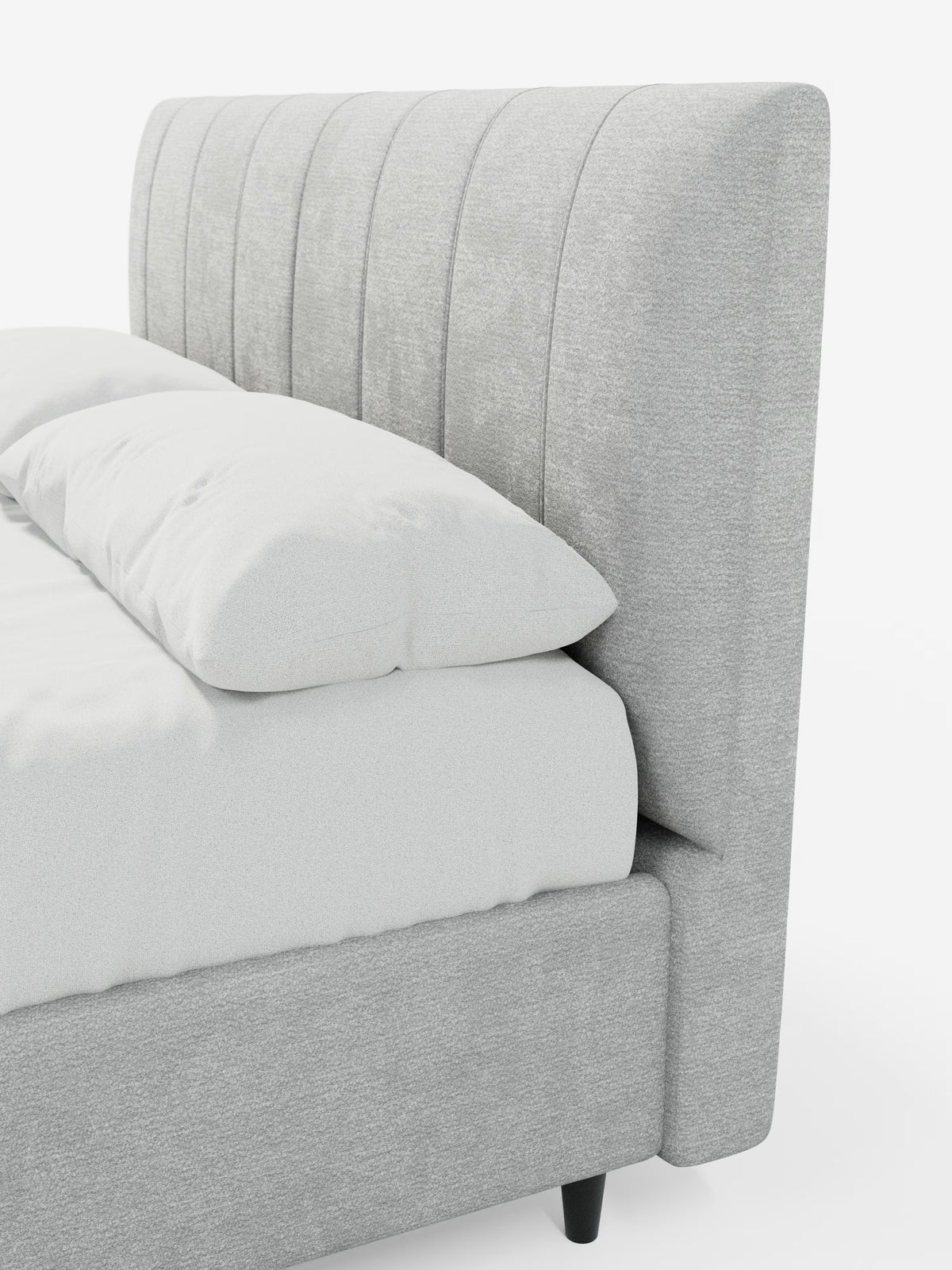 Primo piano del letto imbottito ONYX con contenitore e testiera verticale in tessuto certificato Oeko-Tex® di Letti.store, caratterizzato da una testiera alta di colore grigio chiaro con cuciture verticali. Il letto imbottito presenta una struttura in tessuto coordinato e gambe affusolate di colore nero. Sulla rete sono disposti con cura la biancheria da letto bianca e due cuscini.