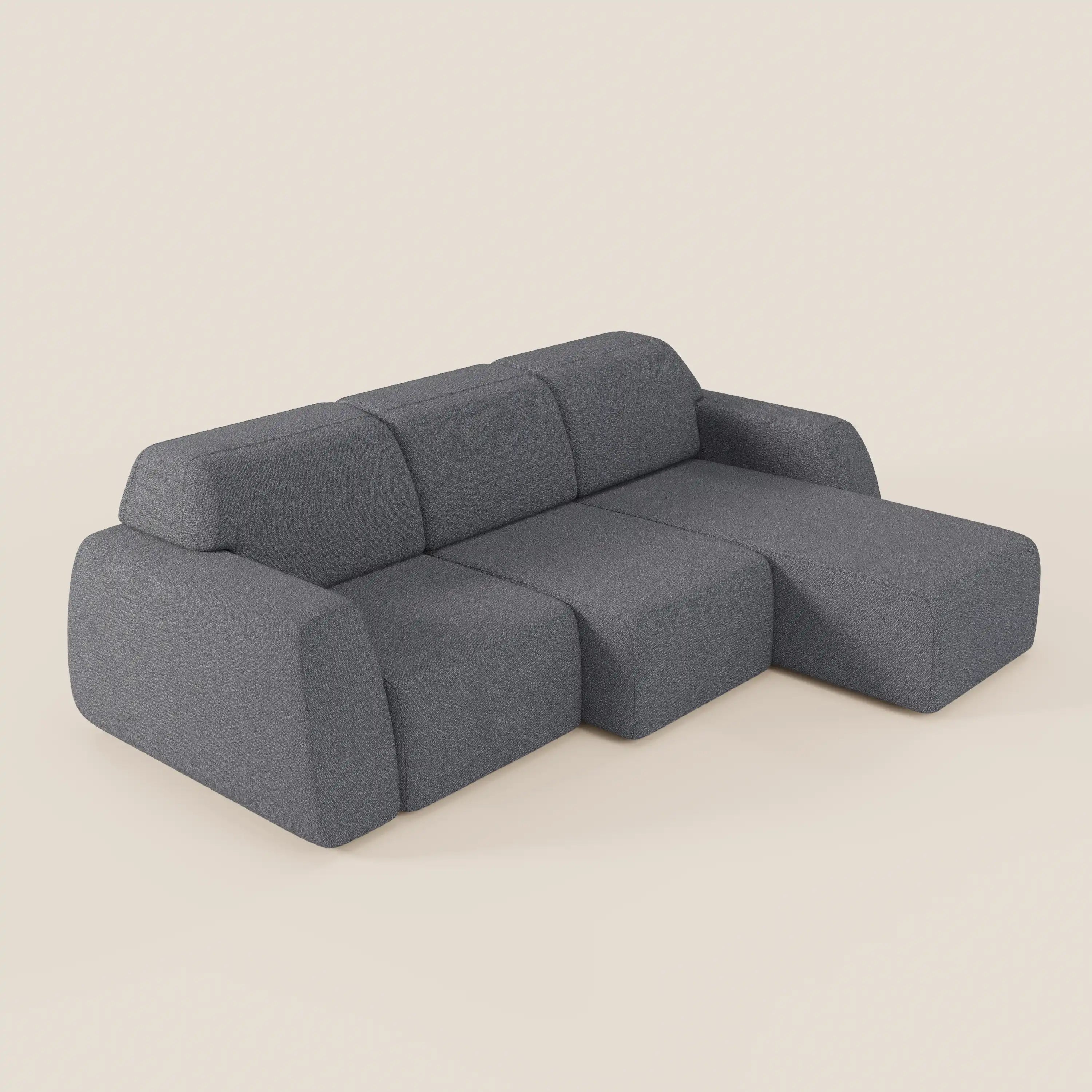 Il divano angolare Orbit di Divani.Store è caratterizzato da una chaise reversibile, da sedute allungabili e da un tessuto antimacchia in cotone effetto T33 dal design moderno e grigio con bordi morbidi, su sfondo beige chiaro.