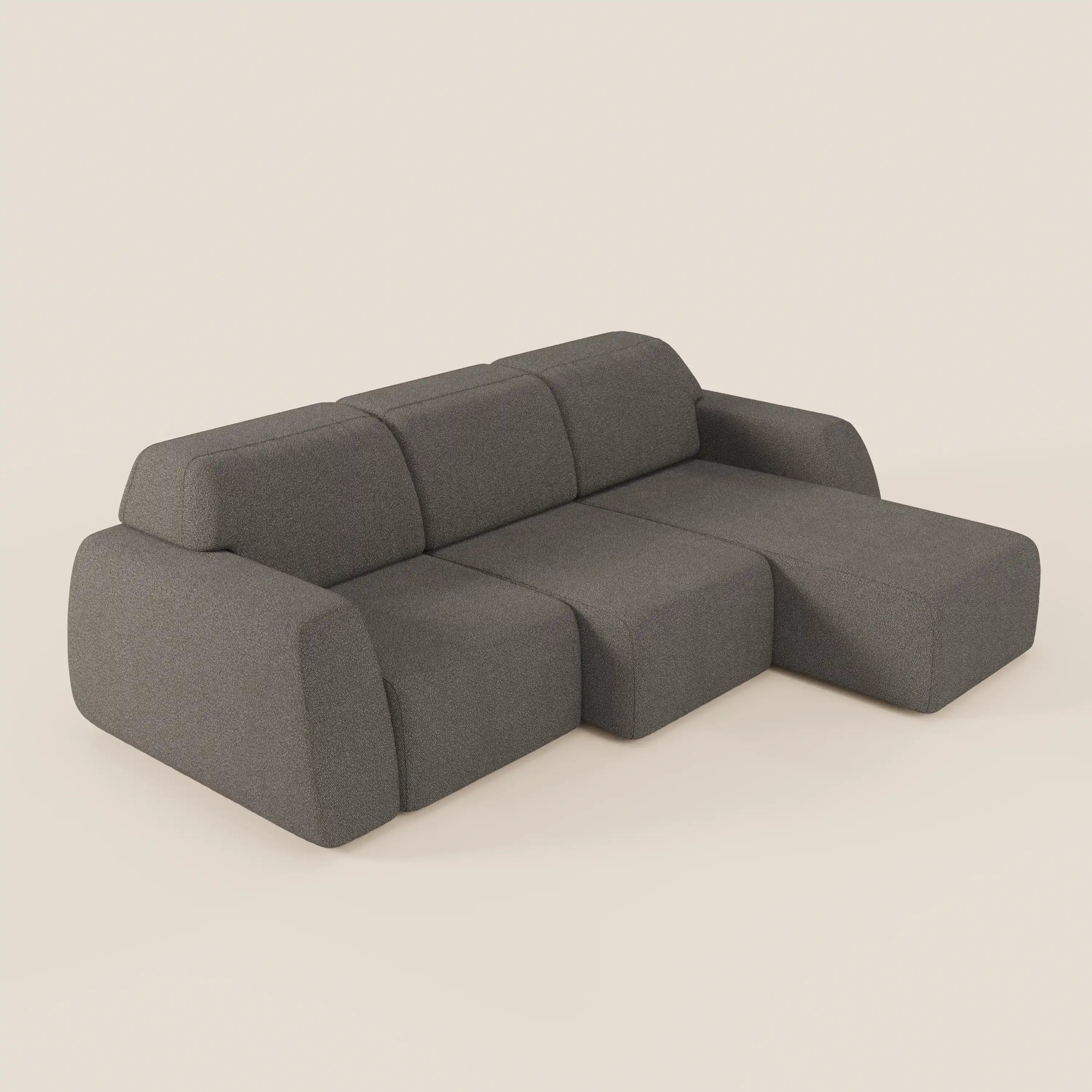 Il Divano angolare Orbit di Divani.Store è caratterizzato da una chaise reversibile, sedute allungabili e tessuto grigio scuro effetto cotone smacchiabile. Gli ampi braccioli arrotondati e i tre cuscini formano una forma a L su uno sfondo chiaro.