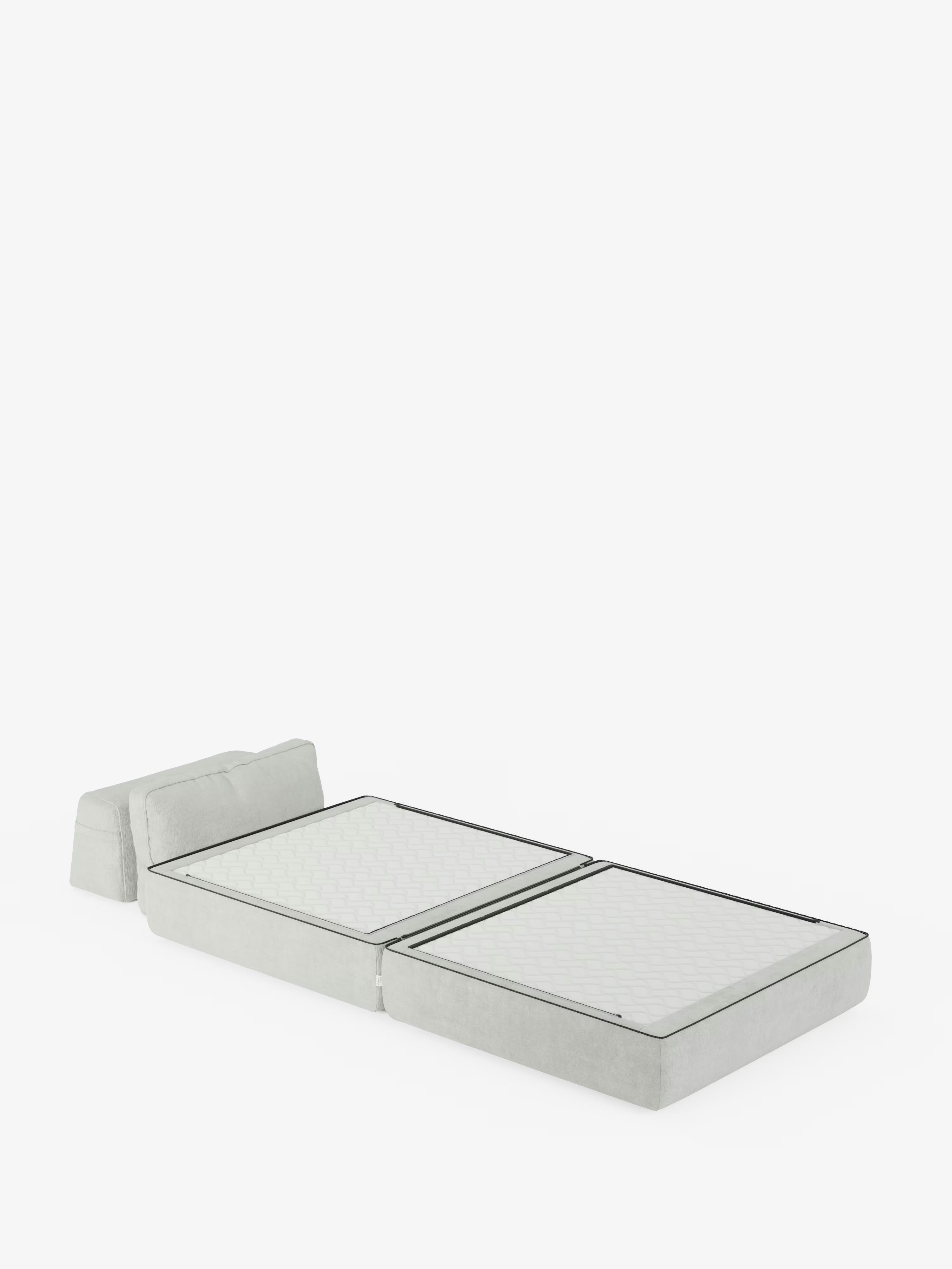 Una moderna poltrona letto Rift dal profilo ribassato, con materasso alto 24 cm e memory foam di Divani.Store, che una volta aperta rivela una base imbottita grigio chiaro e uno schienale orientabile. Questa soluzione trasformabile, realizzata in tessuto smacchiabile T31, presenta un design semplice e minimalista con due sezioni di materasso e una superficie morbida rivestita in tessuto, che risalta su uno sfondo bianco a tinta unita.