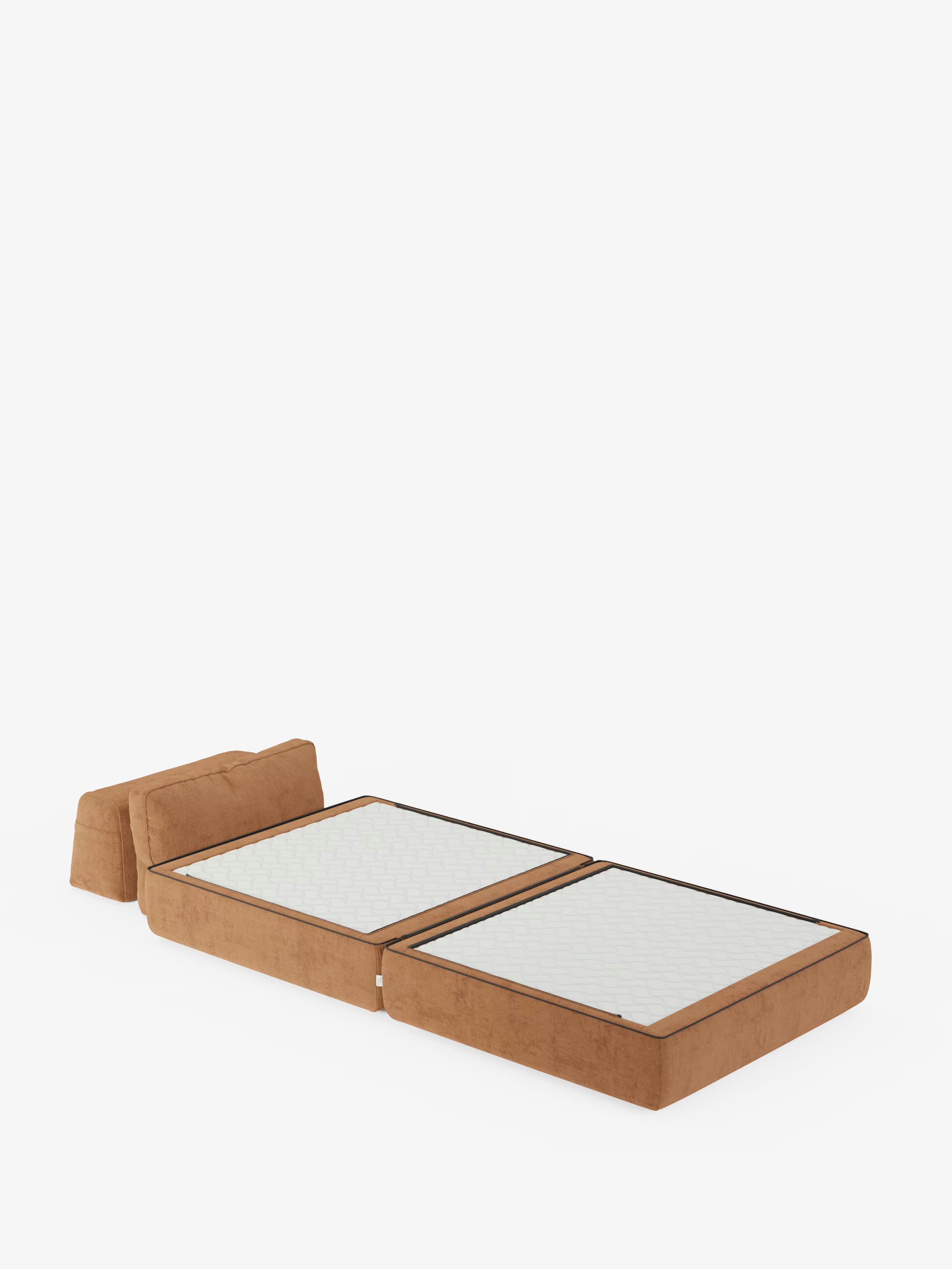 La poltrona letto Rift di Divani.Store, rivestita in tessuto smacchiabile T31, si presenta completamente distesa su uno sfondo bianco. Questa elegante soluzione trasformabile è dotata di un materasso in memory foam alto 24 cm con due distinte sezioni trapuntate bianche e bordi marroni. Lo schienale mobile e i braccioli si ribaltano per formare la testata del letto.