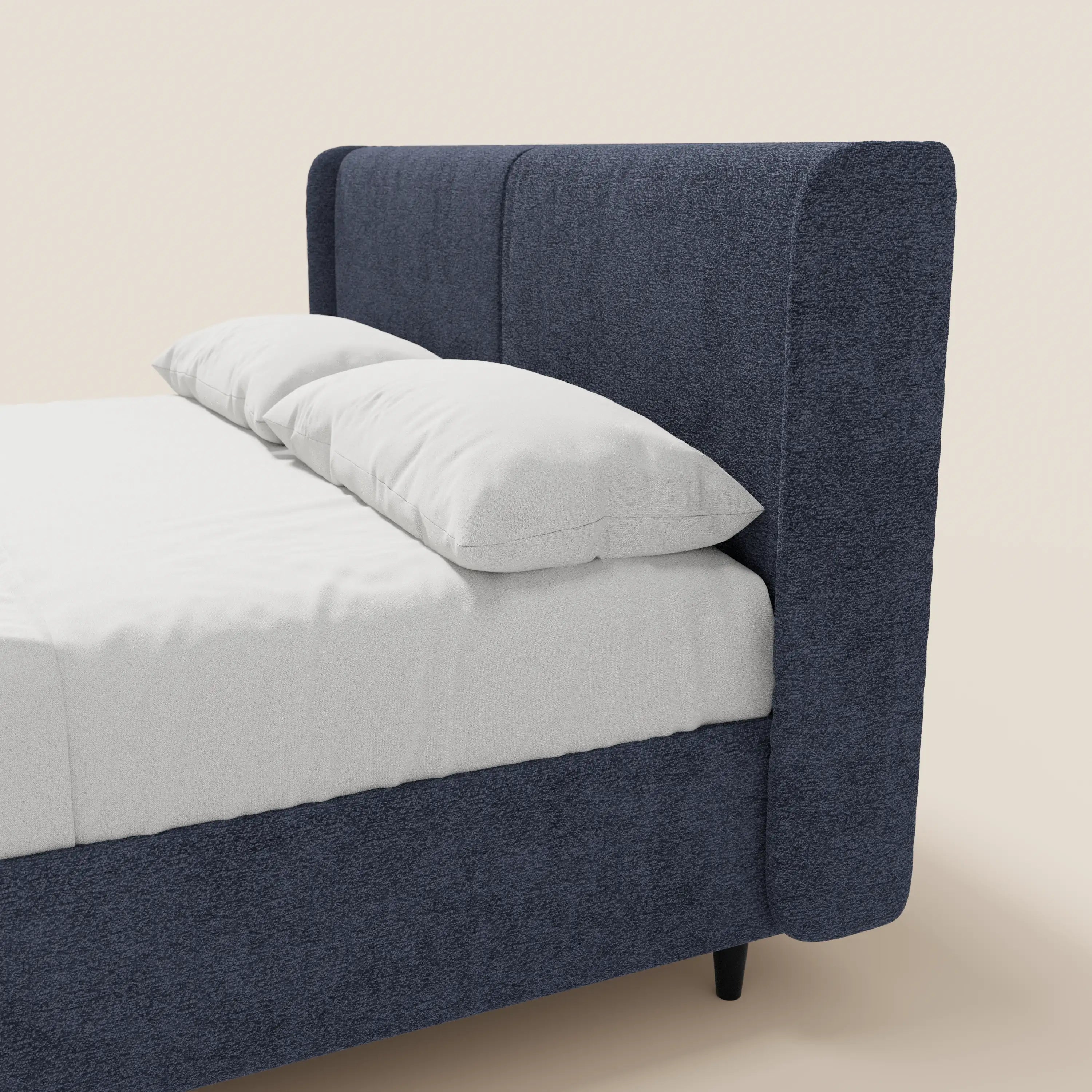 Il letto di design VALKIRIA di Letti.store presenta una struttura rivestita in tessuto blu navy testurizzato certificato Oeko-Tex®, una testiera alta e avvolgente con 2 cuscini imbottiti e un comodo vano contenitore. Abbinato a lenzuola bianche, offre un look raffinato e contemporaneo.