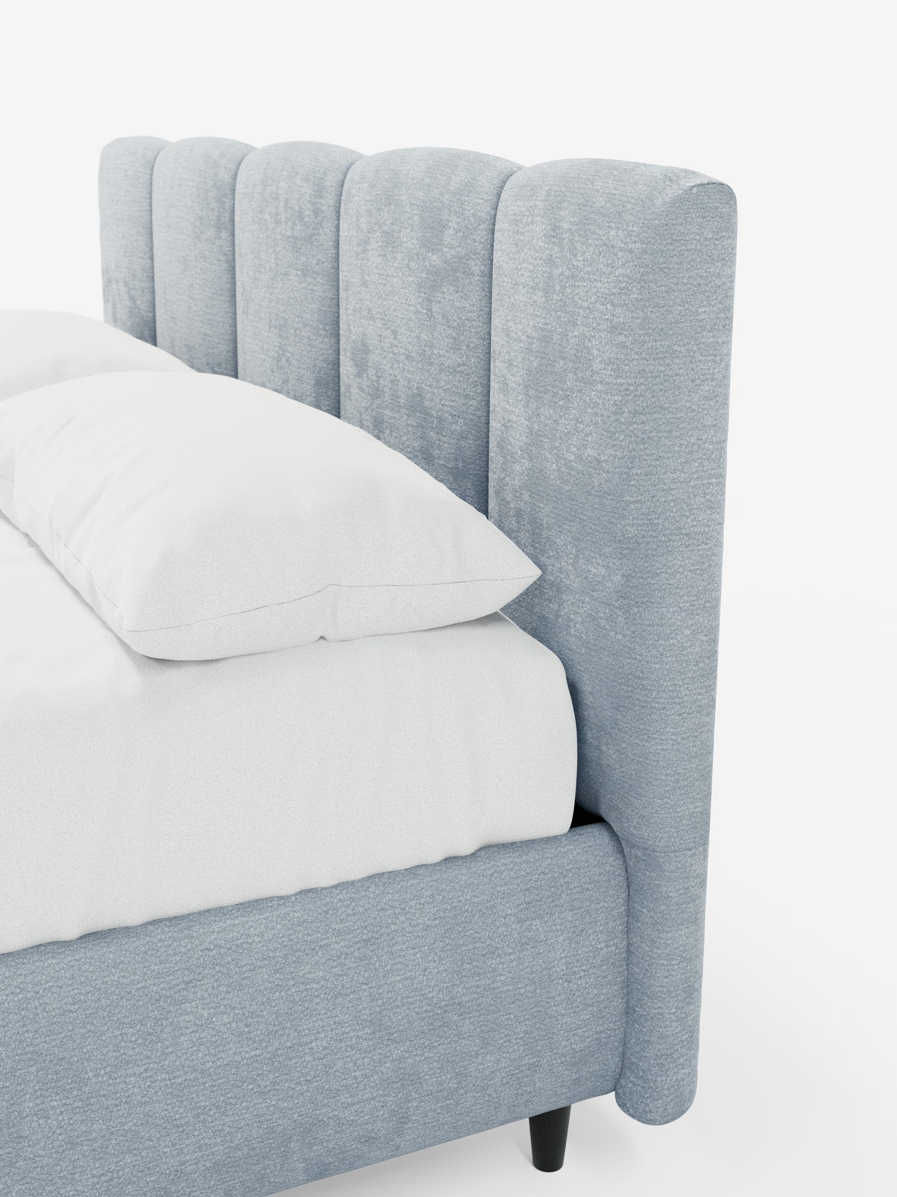 Un letto imbottito ARKAM in stile contemporaneo di Letti.store presenta una testiera alta, di colore grigio chiaro, con dettagli verticali, realizzata in tessuto certificato Oeko-Tex®, con una struttura imbottita abbinata, biancheria da letto bianca e gambe corte scure. Fotografato di profilo, l’immagine mette in risalto il design shabby chic della trama della testiera e mette in mostra morbidi cuscini disposti a strati.