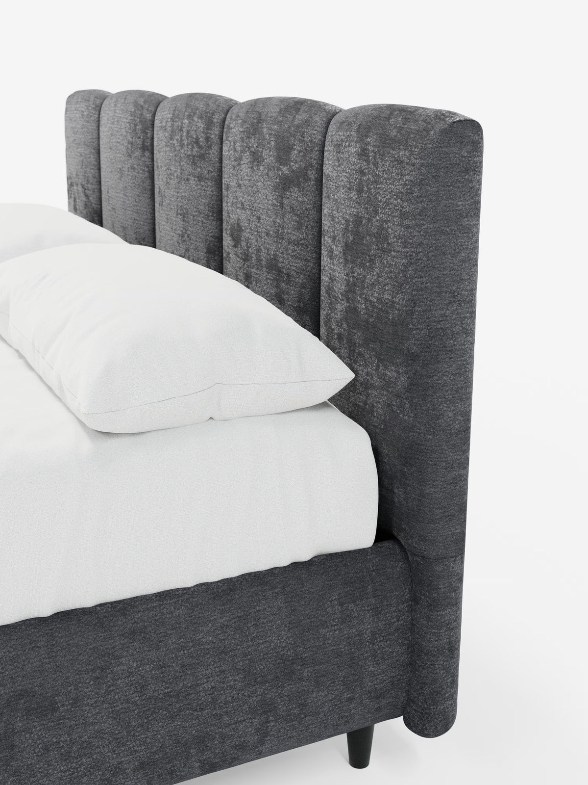 Una vista angolare del letto imbottito ARKAM con contenitore e testiera a lavorazione verticale di Letti.store, che mette in risalto la sua testiera alta e morbida, con dettagli verticali in tessuto certificato Oeko-Tex®. La struttura imbottita abbinata è rivestita con biancheria da letto di un bianco candido e due grandi cuscini bianchi, il tutto su uno sfondo bianco a tinta unita per esaltarne il design shabby chic.