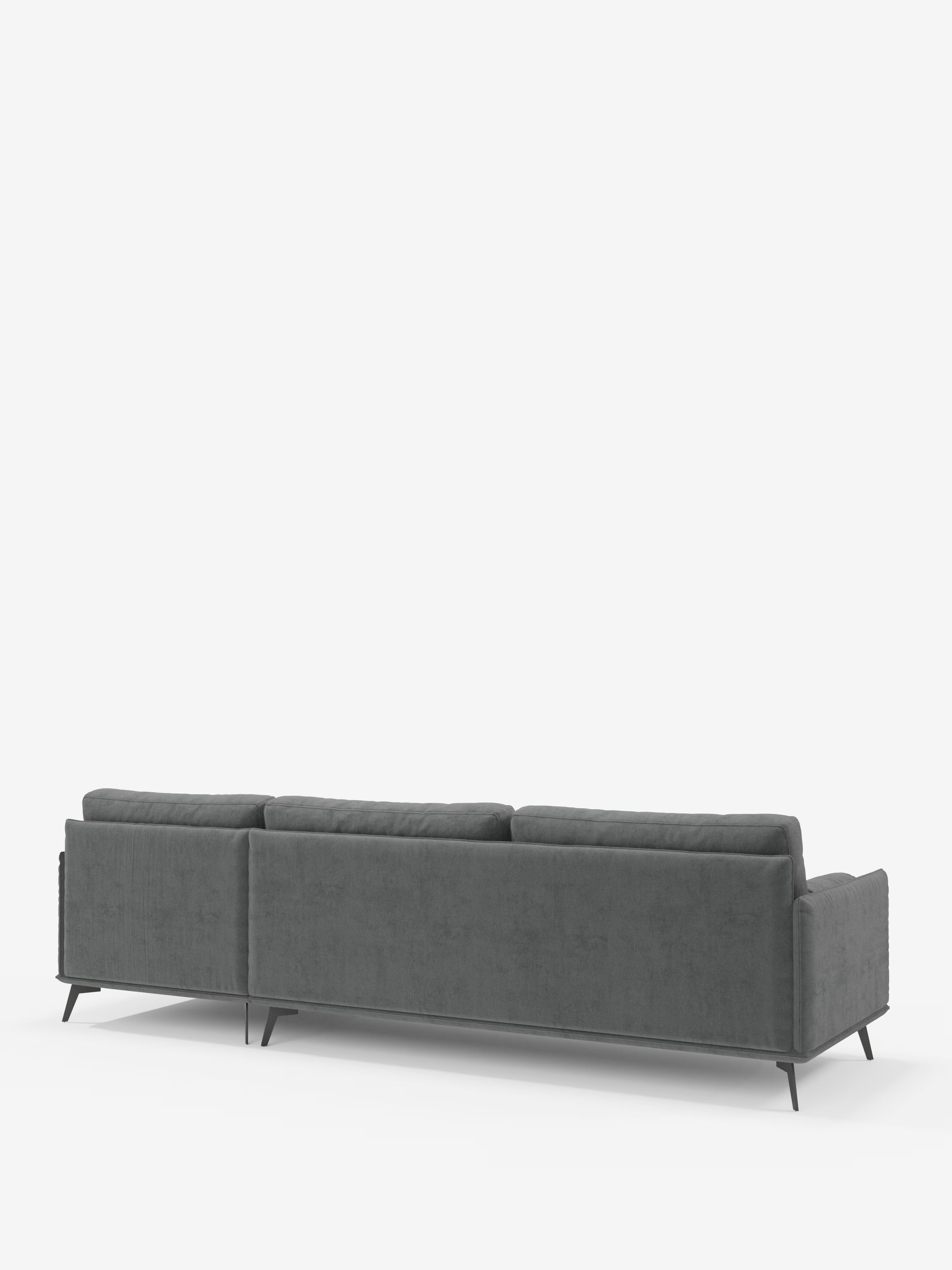 Il divano moderno angolare con penisola Basalto di Divani.Store — qui raffigurato di retro su sfondo bianco — è un divano componibile contemporaneo di colore grigio scuro, dotato di tre cuscini dello schienale imbottiti in piuma e di sottili gambe in metallo nero. Il suo design pulito e minimalista esalta la forma rettangolare e il rivestimento in tessuto T31, liscio e resistente alle macchie, realizzato in Italia.