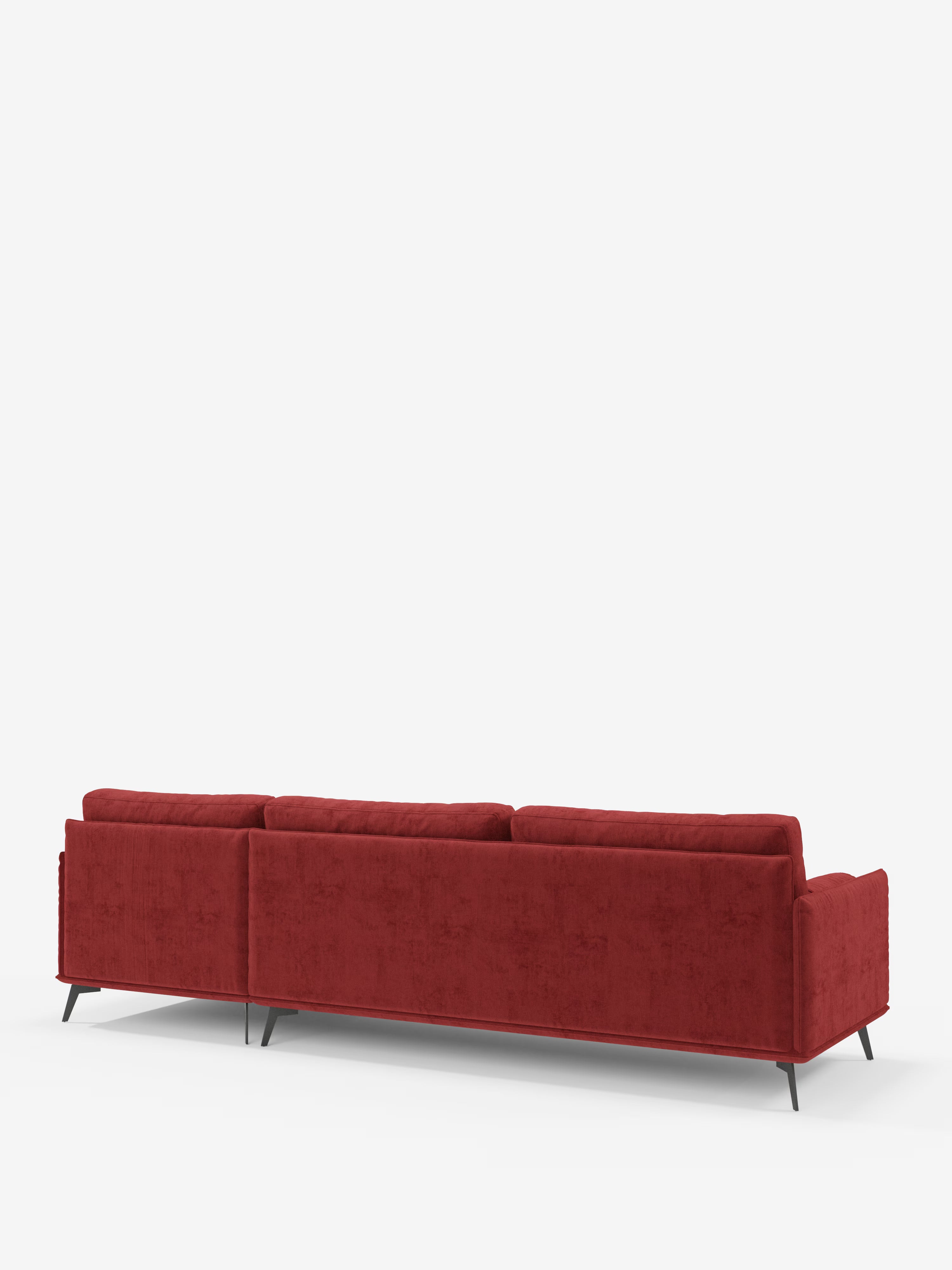 Il divano moderno angolare con penisola Basalto di Divani.Store è un divano italiano contemporaneo in un intenso rosso, dotato di tre cuscini di seduta e qui raffigurato visto da dietro. Questo prodotto Made in Italy vanta un design minimalista con sottili gambe angolari in metallo nero e un rivestimento in tessuto T31 liscio e resistente alle macchie, con cuscini imbottiti in piuma, il tutto su uno sfondo bianco a tinta unita.