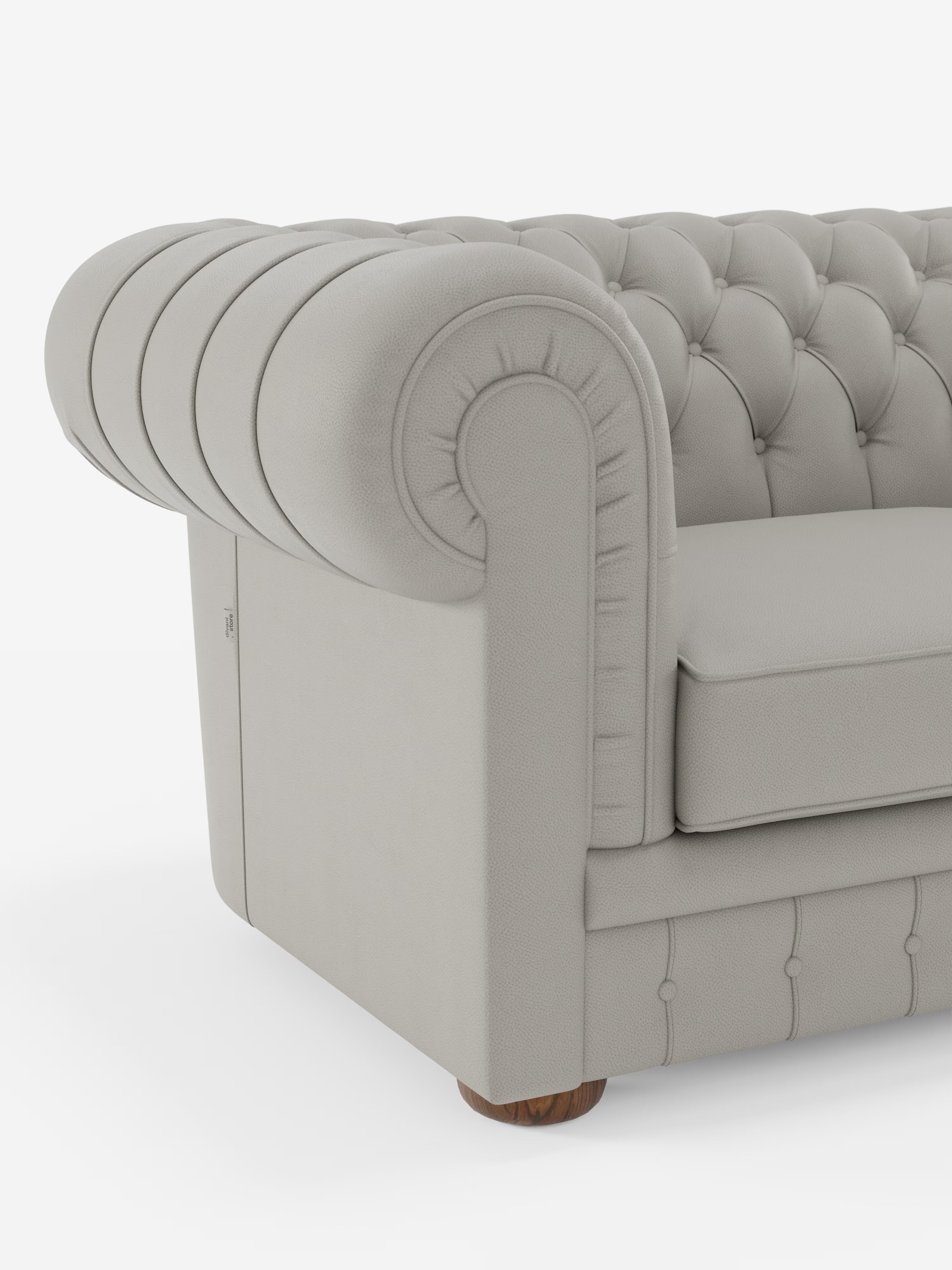 Un primo piano di un Chesterfield grigio chiaro – Divano Chesterfield in vera pelle spessorata a 2 e 3 posti di Divani.Store – mette in risalto i braccioli e lo schienale arrotondati. Entrambi presentano una profonda trapuntatura a bottoni e cuciture dettagliate: elementi intramontabili che caratterizzano questo classico Chesterfield. Il divano poggia con eleganza su una piccola gamba rotonda in legno, in risalto su uno sfondo bianco pulito.