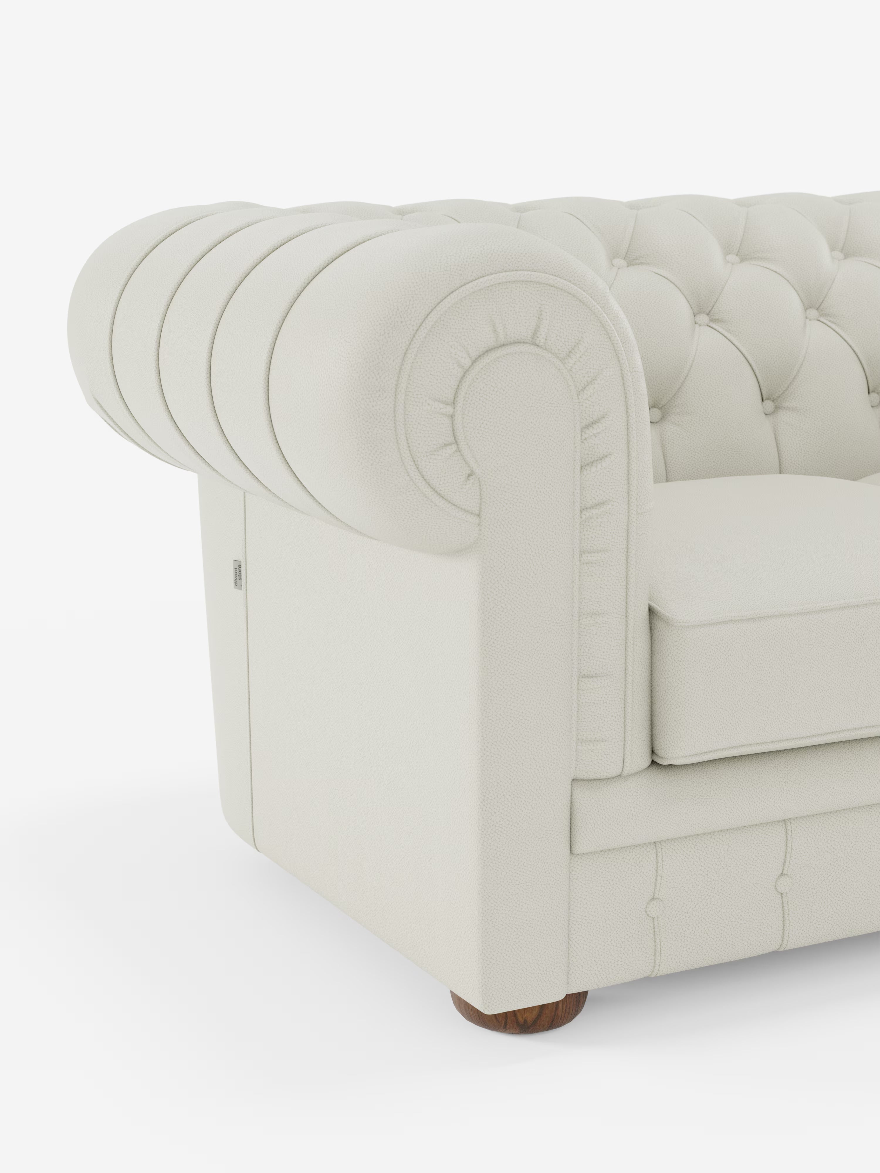 Primo piano del bracciolo del divano “Chester 4 Posti 3 sedute in Vera Pelle – Chesterfield Capitonné Artigianale” di Divani.Store, caratterizzato da un rivestimento in vera pelle color crema con finitura testurizzata, capitonné profondo, bracciolo arrotondato e piedini in legno. Realizzato in Italia, il design classico ed elegante del divano risalta sullo sfondo bianco a tinta unita.