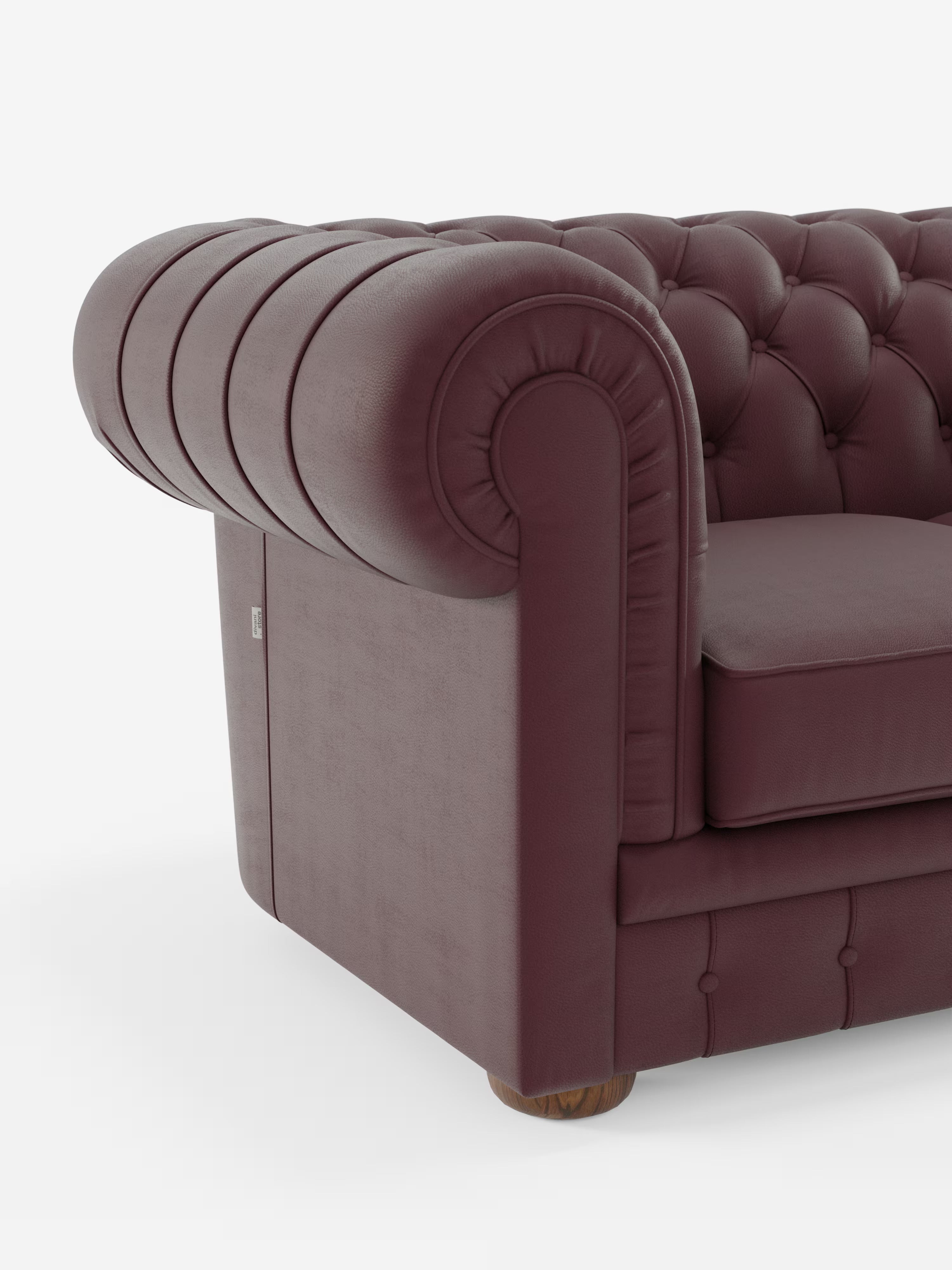 Primo piano del Divani.Store Chester 4 Posti 3 sedute in Vera Pelle – Chesterfield Capitonné Artigianale, che mette in risalto il rivestimento in vera pelle bordeaux con schienale capitonné, braccioli arrotondati caratterizzati da profonde pieghe e morbido cuscino di seduta. L’angolo del divano lascia intravedere il pavimento in legno sottostante, che fa da contrasto allo sfondo bianco.