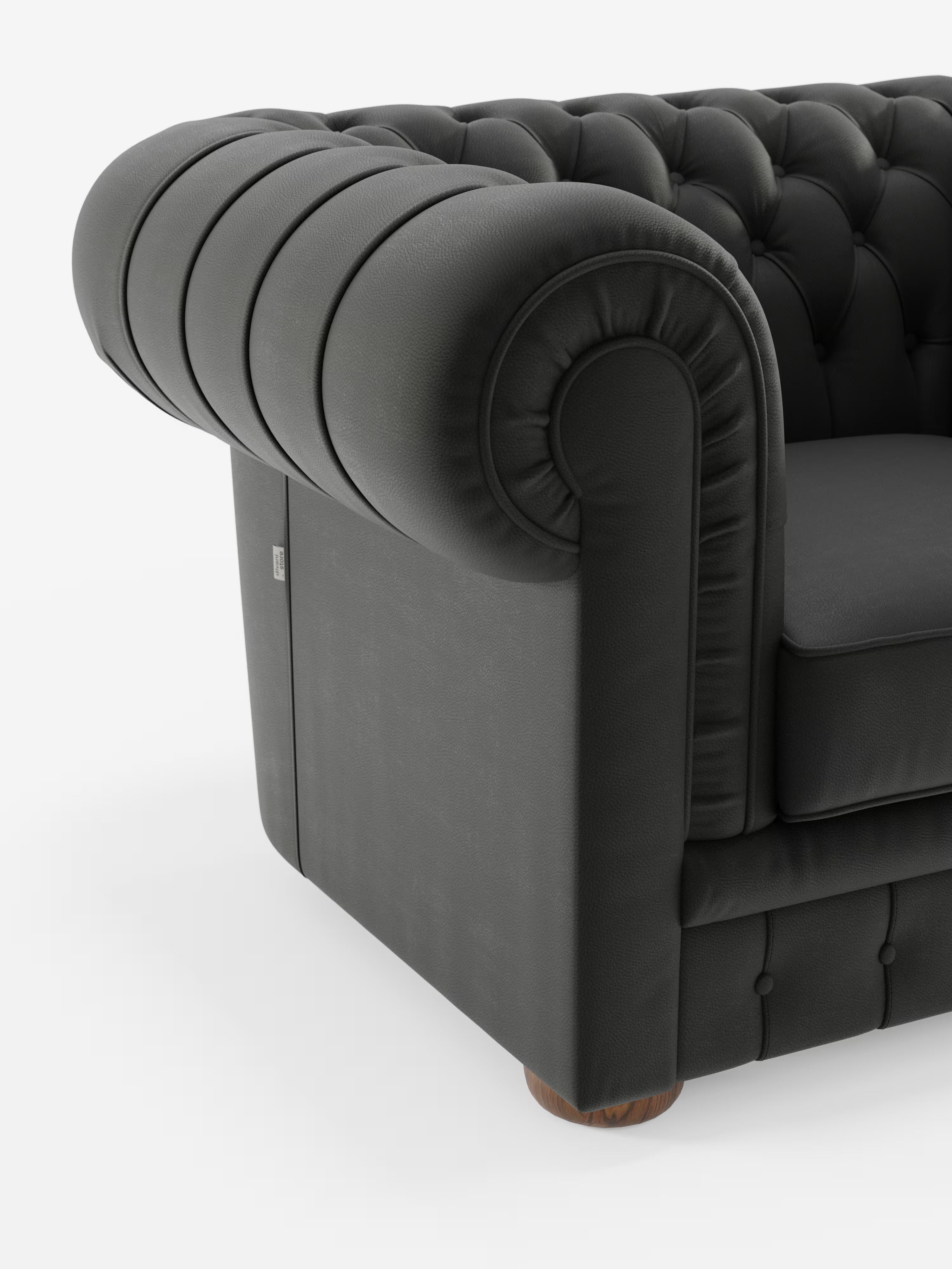 Un primo piano della poltrona Chester in vera pelle spessorata con capitonné artigianale di Divani.Store mette in risalto il bracciolo in pelle nera arrotondata, la profonda trapuntatura artigianale tipica delle classiche poltrone capitonné e il rivestimento testurizzato. La gamba in legno a vista e il morbido cuscino completano il suo aspetto intramontabile ed elegante su uno sfondo bianco a tinta unita.