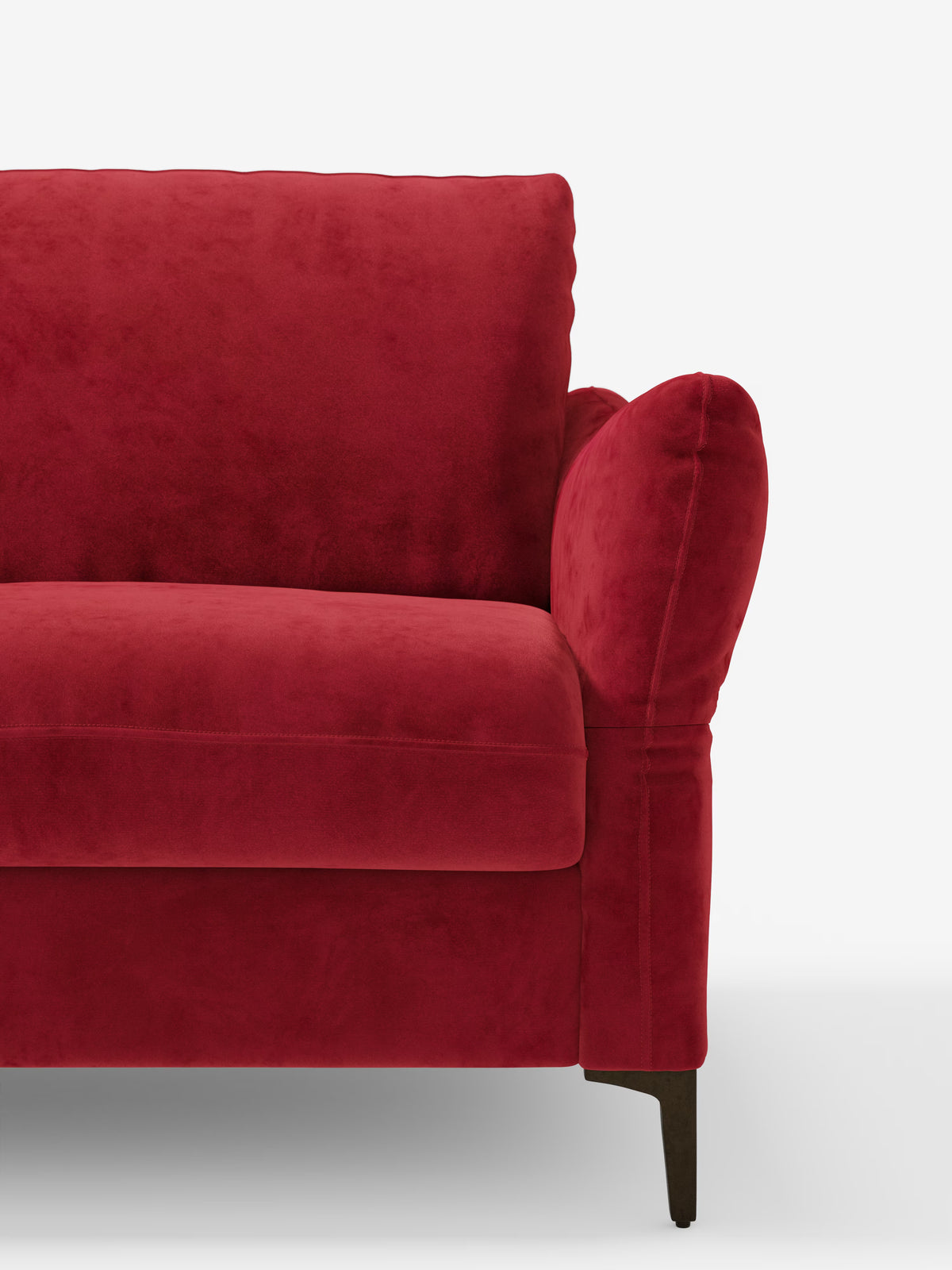 Un primo piano del divano letto Dalia di Divani.Store — qui presentato nella versione T30 Modern, in vivace velluto rosso antimacchia — mette in risalto i morbidi cuscini della seduta e dello schienale, i braccioli arrotondati e le gambe in legno scuro. Su uno sfondo bianco a tinta unita che ne accentua la ricca trama e il colore deciso, è visibile solo la metà sinistra di questo divano letto contemporaneo.