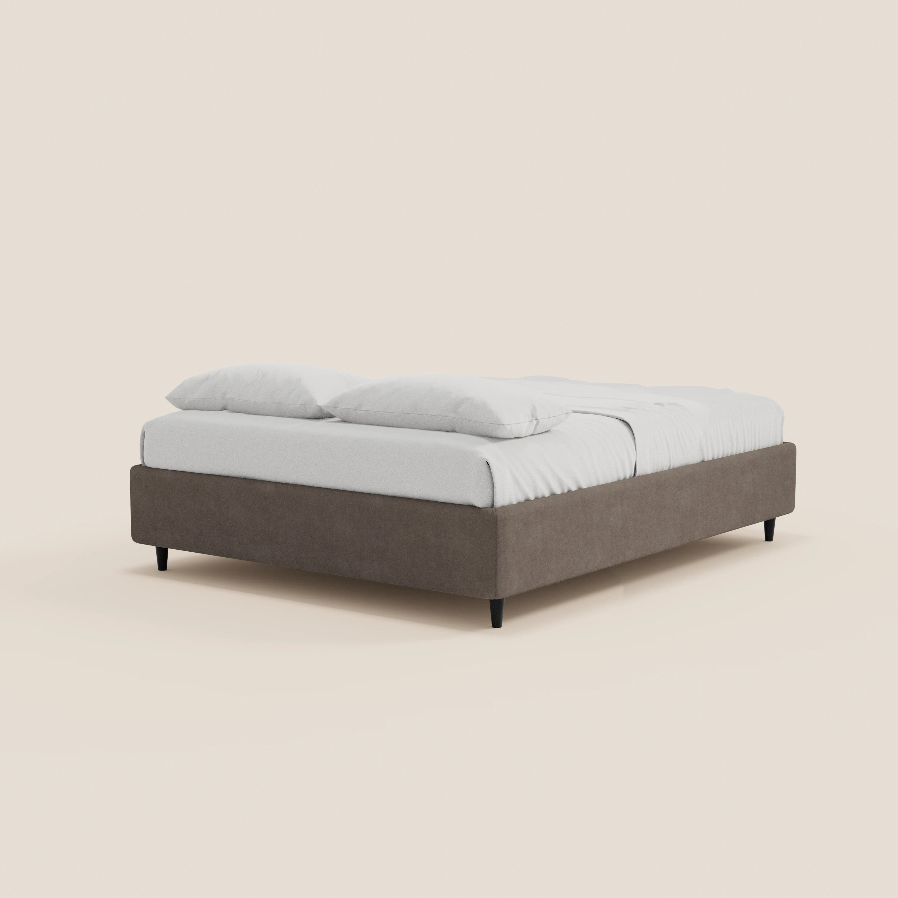 Il letto sommier ERON di Letti.store è un letto moderno caratterizzato da una struttura bassa e rettangolare rivestita in grigio (tessuto impermeabile certificato Oeko-Tex), biancheria da letto bianca e due cuscini bianchi. Poggia su corte gambe nere e si inserisce in uno sfondo bianco sporco, in uno stile minimalista.