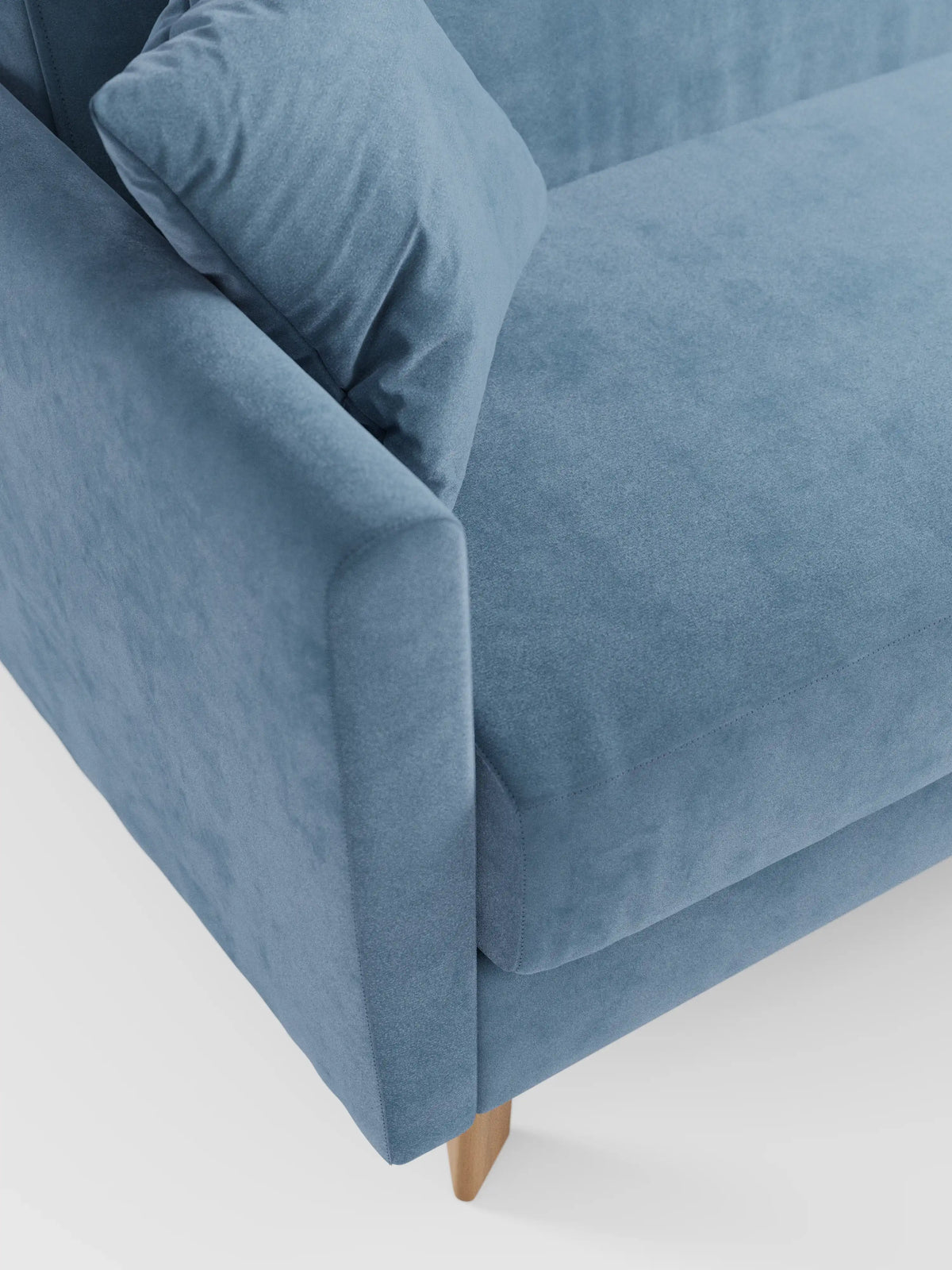 Un primo piano del divano letto Francy con poggiatesta regolabili di Divani.Store in azzurro, con bracciolo sinistro, cuscino di seduta e un cuscino coordinato. Questo moderno divano letto poggia su gambe in legno su uno sfondo bianco, mettendo in risalto il suo elegante tessuto T30 smacchiabile dalla texture morbida, completamente sfoderabile.
