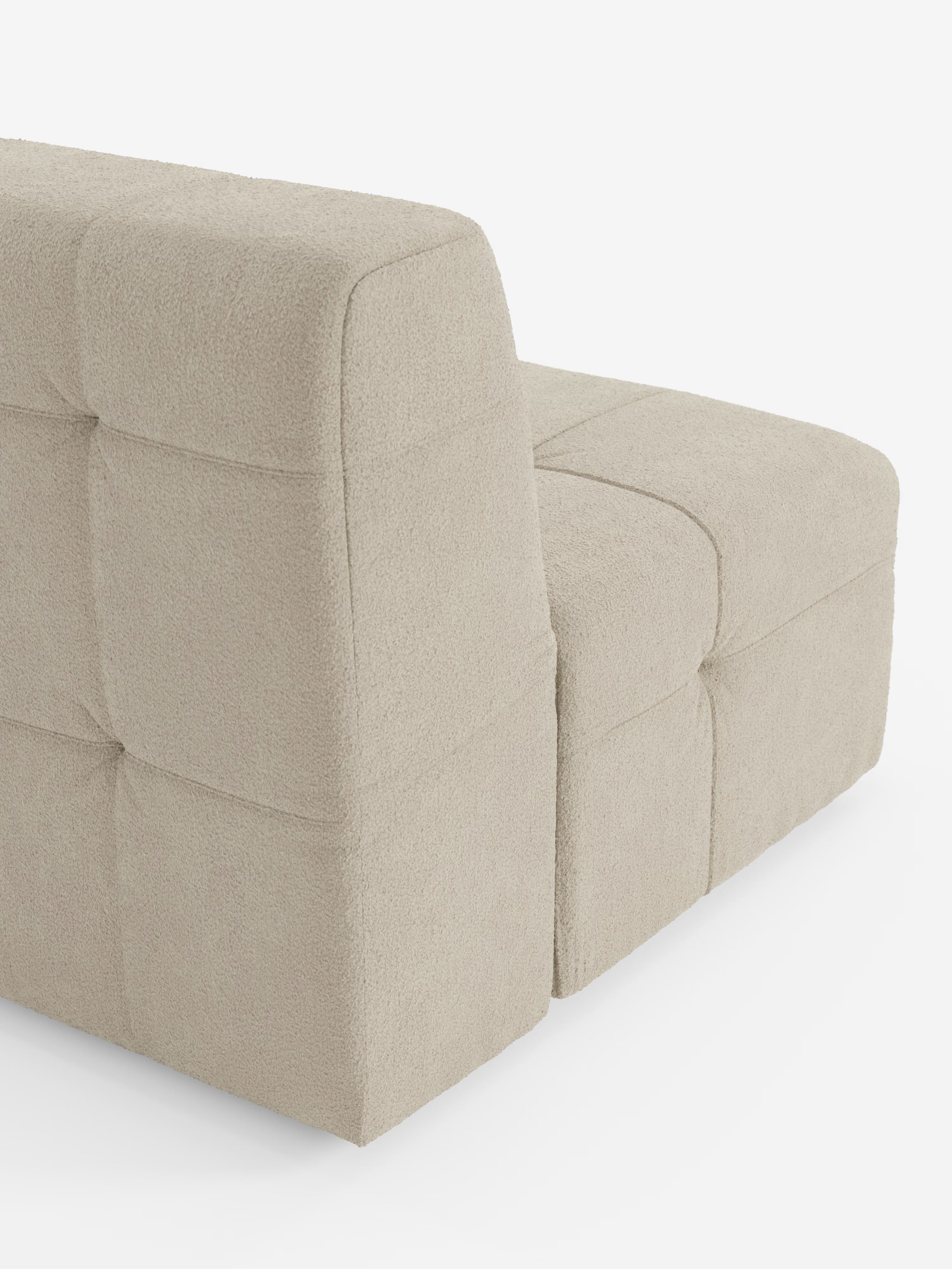Un divano moderno e modulare in tessuto bouclé beige con finitura T21 antimacchia, ispirato al design delle poltrone di Divani.Store. La poltrona Mosaic modulo da 77 cm presenta sezioni quadrate imbottite con lavorazione capitonné e sedute profonde, raffigurata in una vista posteriore obliqua su sfondo bianco.