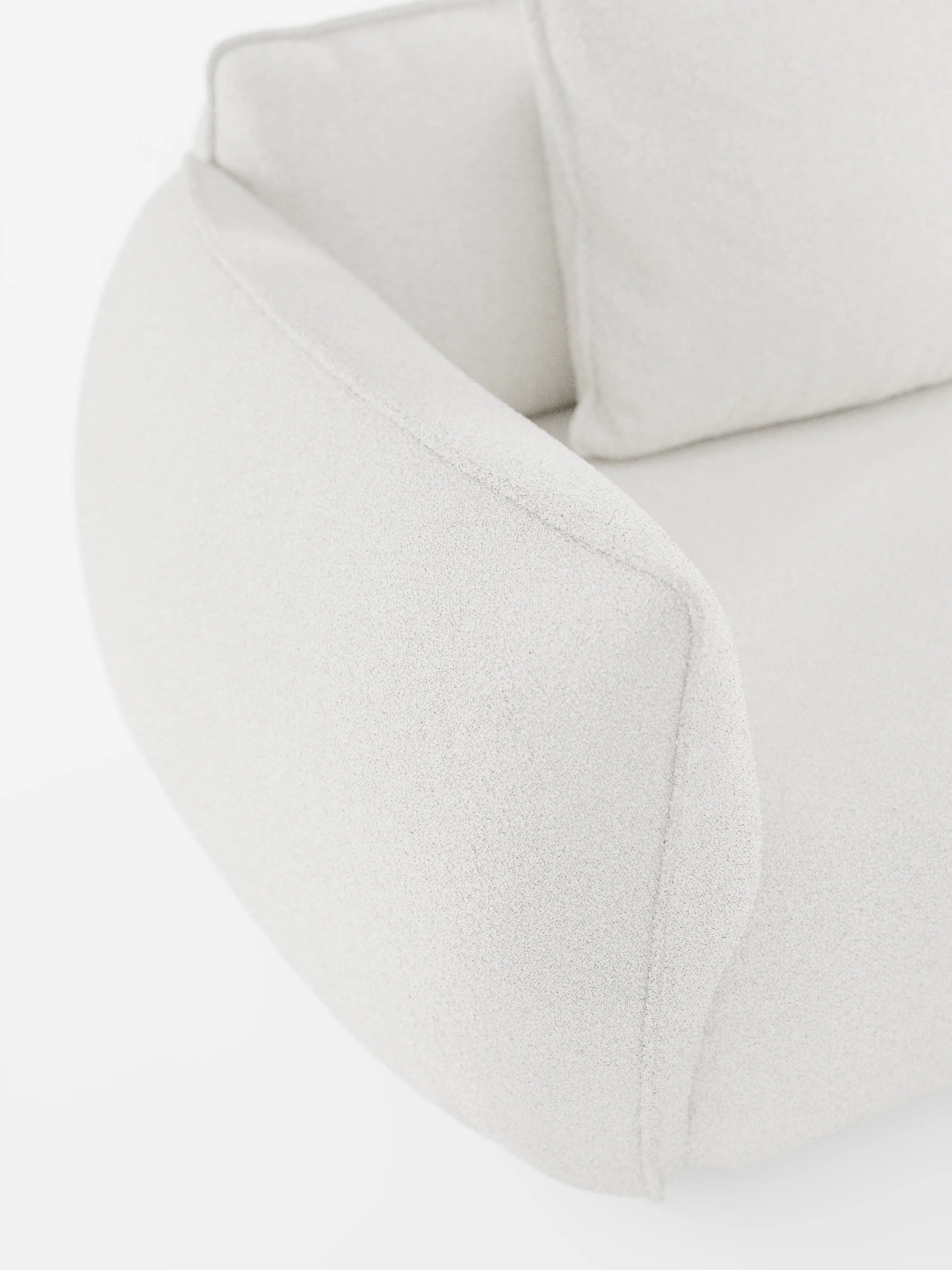 Primo piano del divano modulare a 3 posti “Nimbus” di Divani.Store, caratterizzato da un morbido rivestimento bianco sporco con texture in tessuto smacchiabile effetto cotone T33. L’immagine mette in risalto il bracciolo arrotondato, le cuciture lisce e una parte del cuscino di seduta su uno sfondo bianco a tinta unita. Con il suo design minimalista e accogliente, che ricorda i divani componibili contemporanei, questo modello di Divani.Store dona un'eleganza naturale a qualsiasi ambiente del soggiorno.