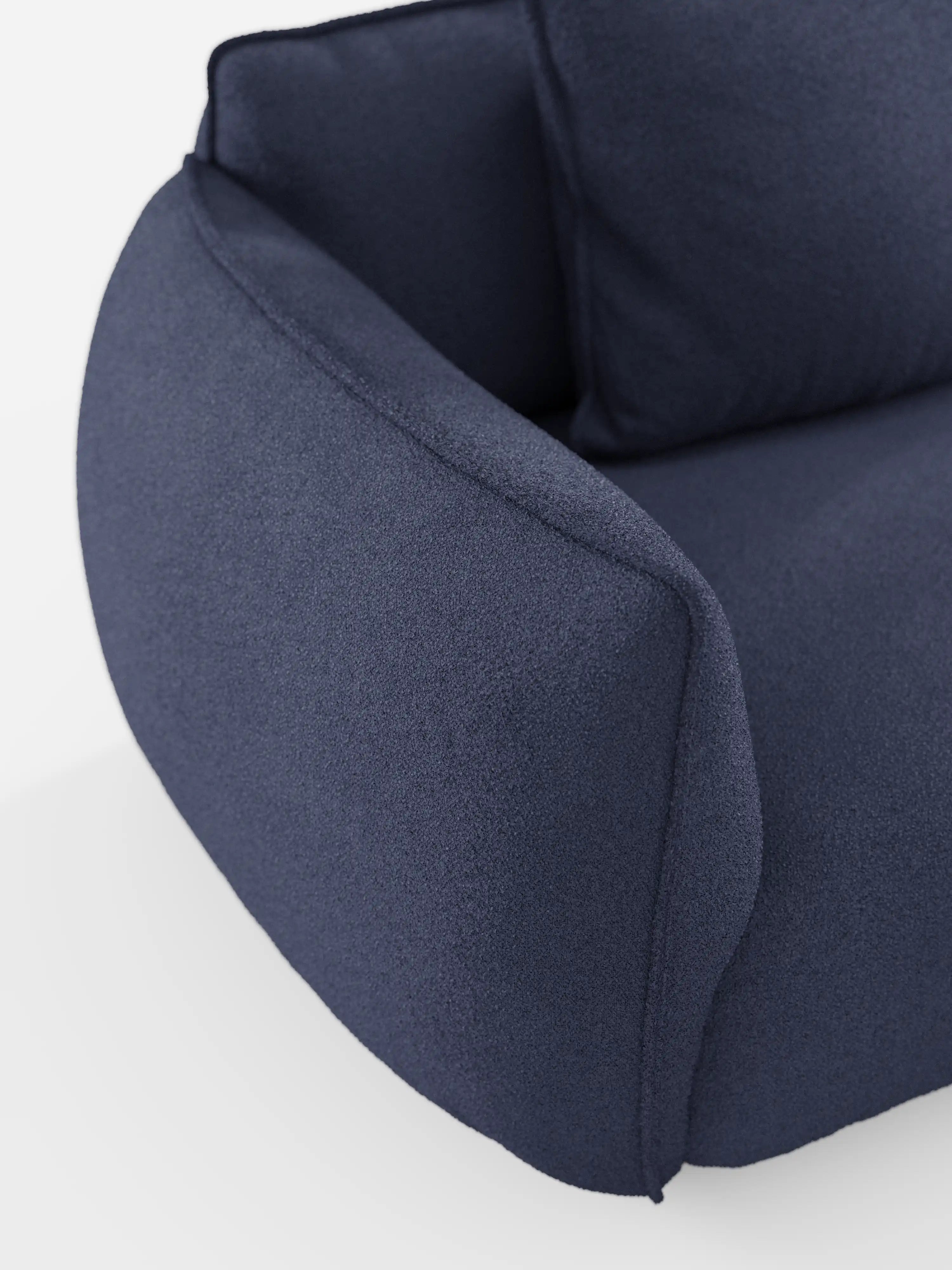 Un primo piano del divano modulare a 3 posti “Nimbus” di Divani.Store mette in risalto il suo tessuto effetto cotone di colore blu intenso, dalla trama morbida e resistente alle macchie. I braccioli arrotondati e i soffici cuscini dello schienale sottolineano il comfort accogliente e il design avvolgente di questo moderno divano modulare, in risalto su uno sfondo bianco a tinta unita.