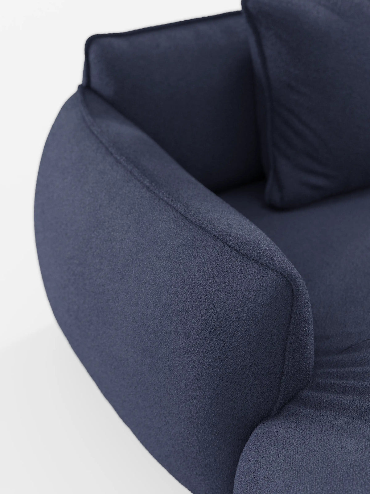 Primo piano del divano angolare modulare panoramico Nimbus con penisola e design angolare, rivestito in tessuto t33 blu intenso resistente alle macchie, caratterizzato da braccioli curvi e da un cuscino coordinato. Presentato su uno sfondo bianco a tinta unita, il materiale morbido e materico mette in risalto la raffinata maestria artigianale che contraddistingue i mobili Made in Italy di Divani.Store.