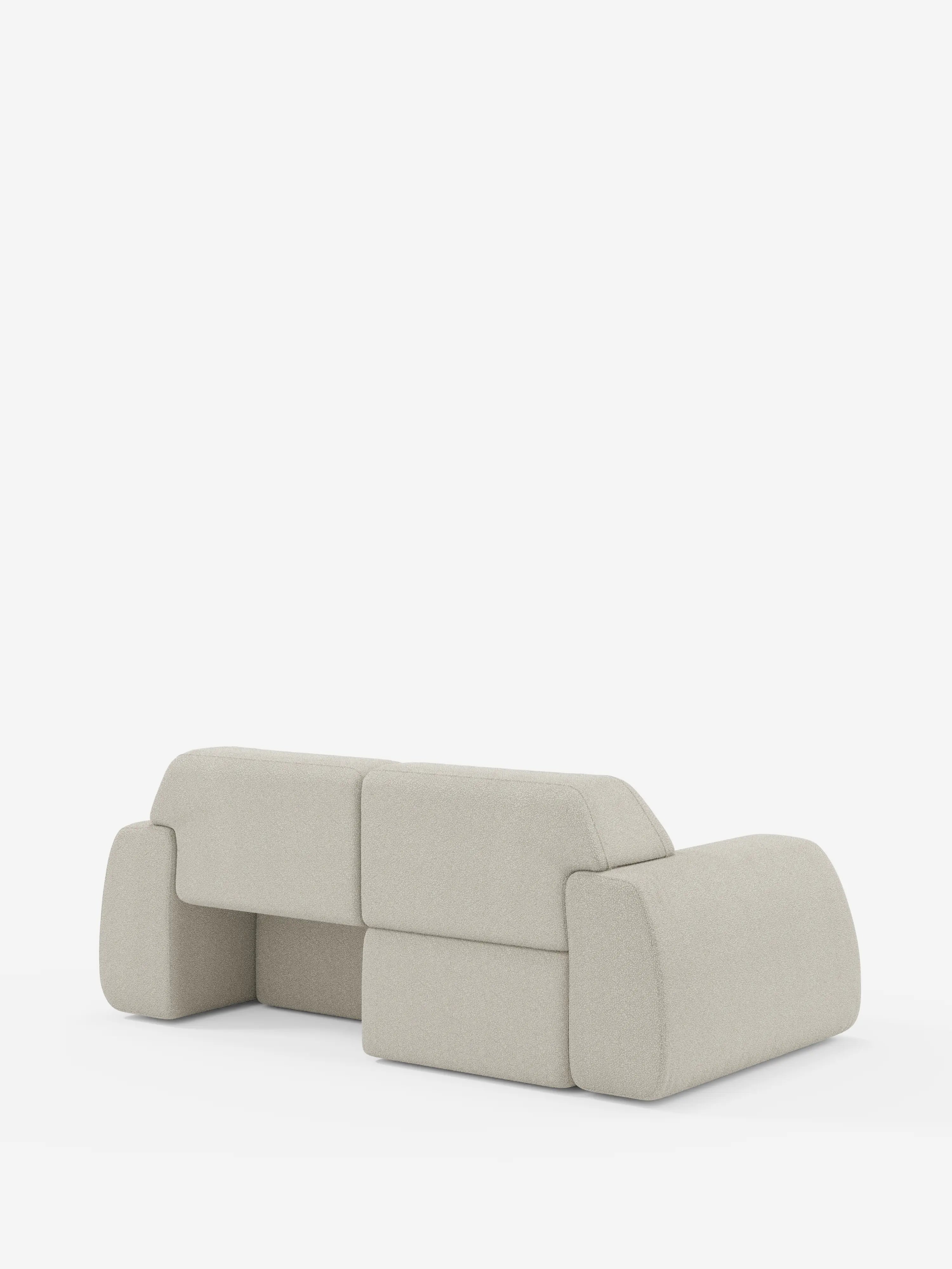 Un moderno divano Orbit a 2 e 3 posti con sedute scorrevoli di Divani.Store, rivestito in tessuto T33 grigio chiaro, antimacchia ed effetto cotone, caratterizzato da bordi arrotondati e cuscini dalla forma geometrica squadrata. Ripreso di retro su uno sfondo bianco, questo modello completamente sfoderabile presenta un design minimalista, privo di gambe a vista o elementi decorativi.
