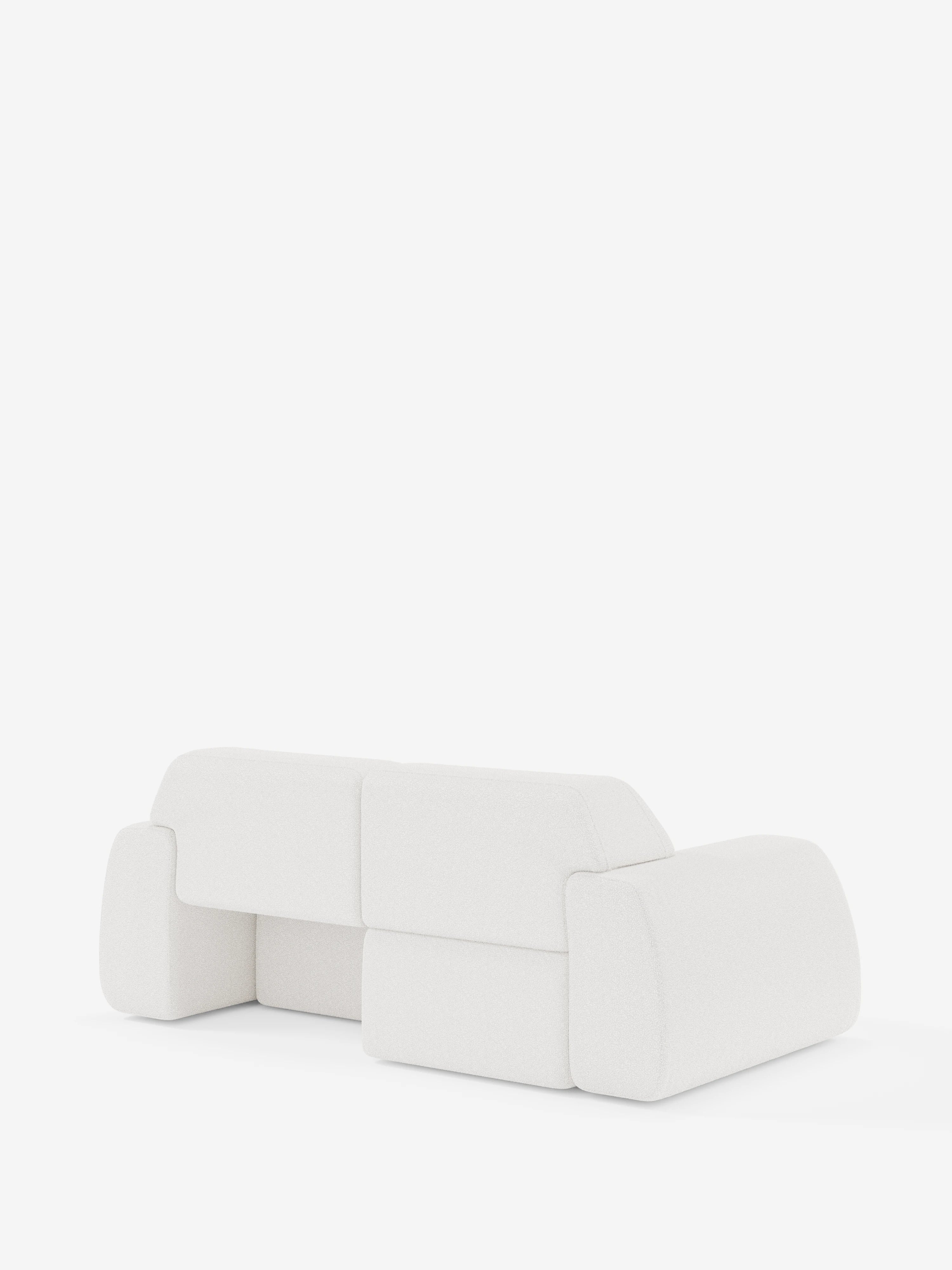 Il divano a 3 posti Orbit di Divani.Store, rivestito in tessuto T33 effetto cotone, resistente alle macchie e completamente sfoderabile, è qui presentato in bianco. Il suo design moderno e minimalista è caratterizzato da bordi morbidi e arrotondati e da cuscini dalla forma squadrata. Ritratto di spalle e leggermente di profilo su uno sfondo bianco a tinta unita, il divano mette in risalto la sua estetica lineare e semplice.