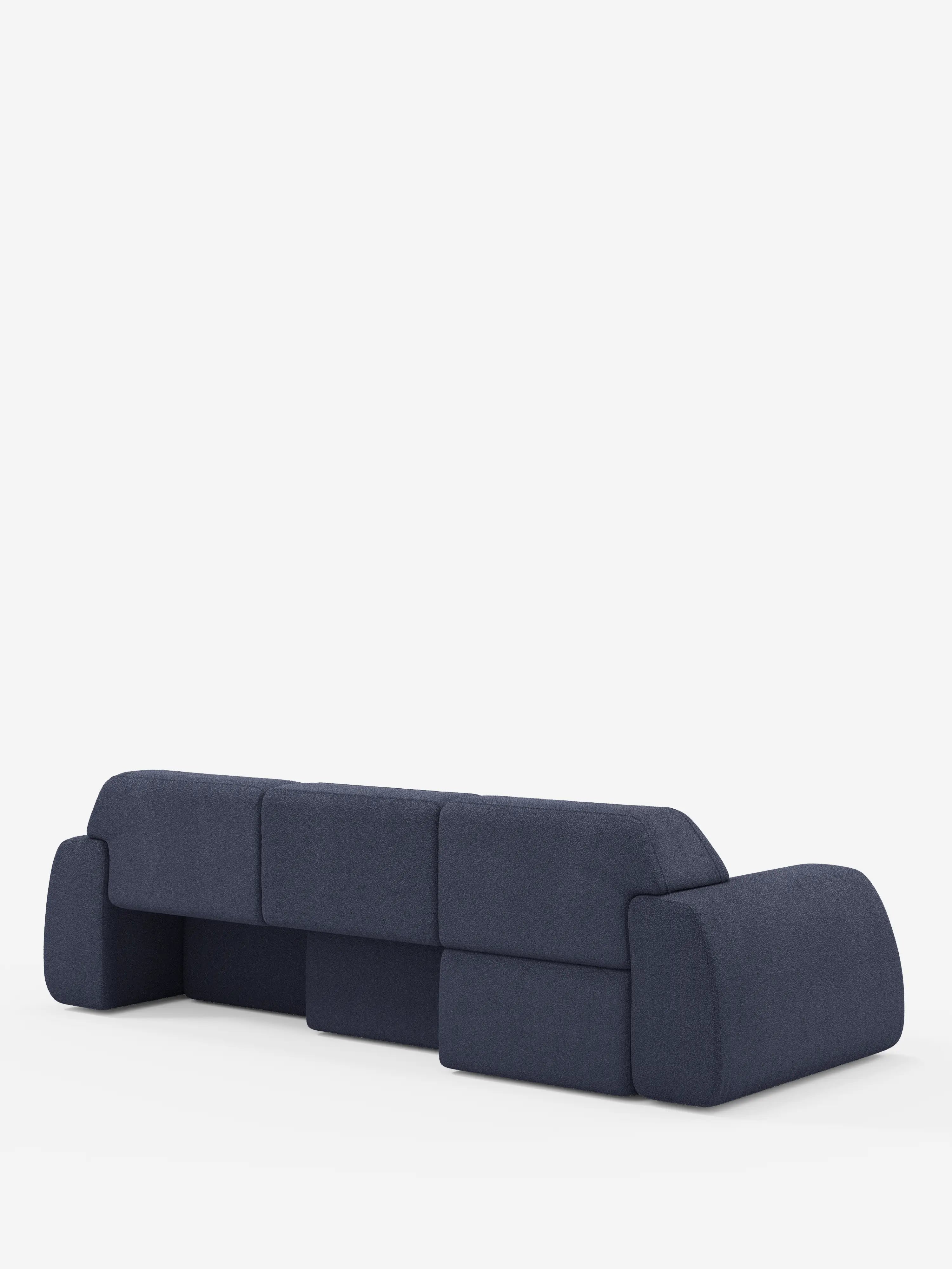 Il moderno divano angolare Orbit con penisola reversibile e tutte le sedute allungabili, rivestito in tessuto smacchiabile effetto cotone T33 di Divani.Store, è qui raffigurato visto da dietro in un intenso blu navy. È caratterizzato da cuscini spessi e squadrati e da braccioli bassi e arrotondati. Lo sfondo completamente bianco mette in risalto il design audace e geometrico del divano.