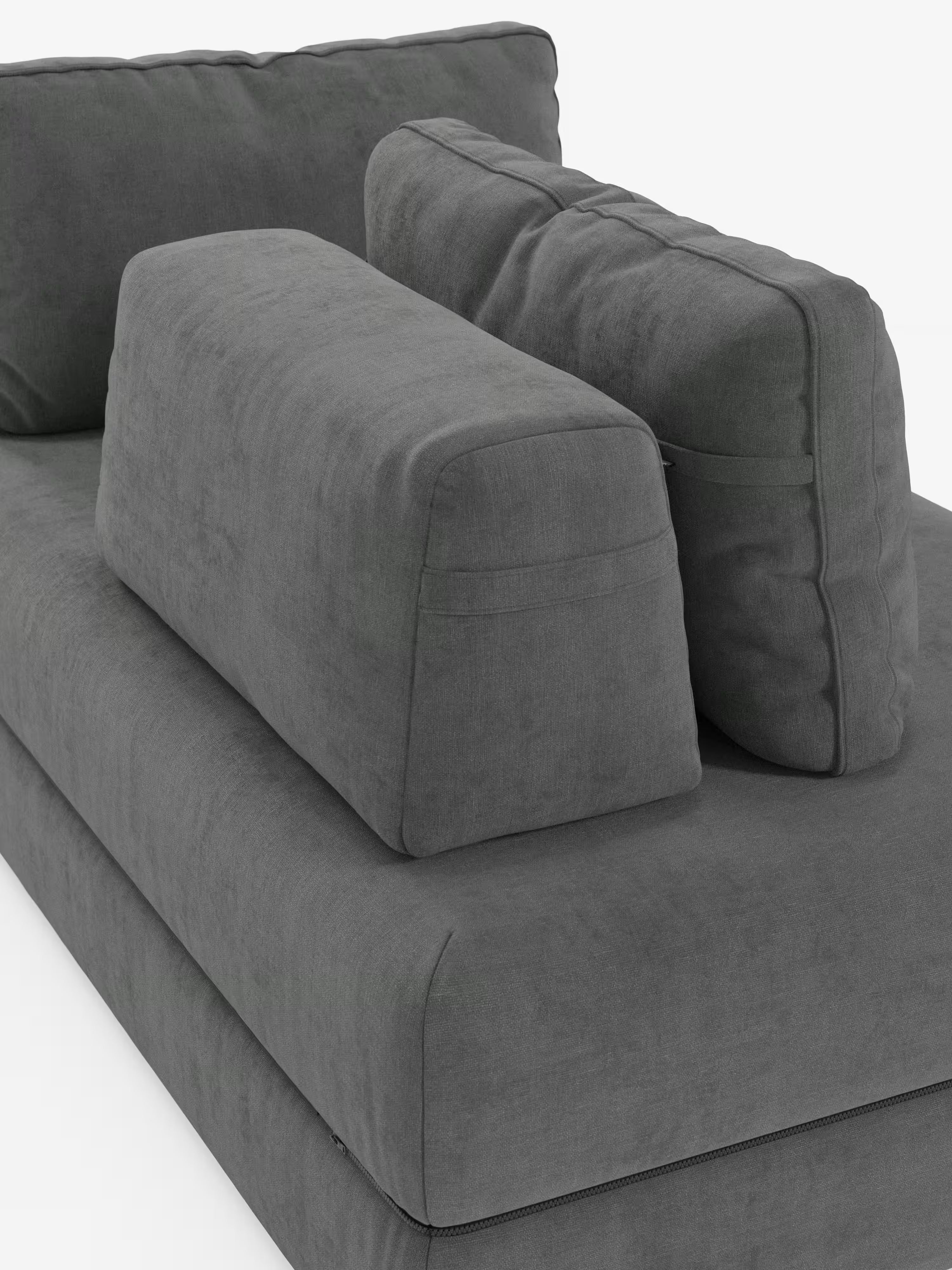 Un primo piano del moderno divano letto matrimoniale Rift a 2 e 3 posti con schienali mobili di Divani.Store — rivestito in tessuto T31 grigio scuro e resistente alle macchie — mostra due spessi cuscini rettangolari per lo schienale e un grande cuscino a forma di cuneo posizionato in diagonale contro di essi. Questo versatile divano letto è dotato di un materasso in memory foam alto 24 cm ed è posizionato su uno sfondo bianco a tinta unita. Tutti i cuscini sono rivestiti con lo stesso tessuto.