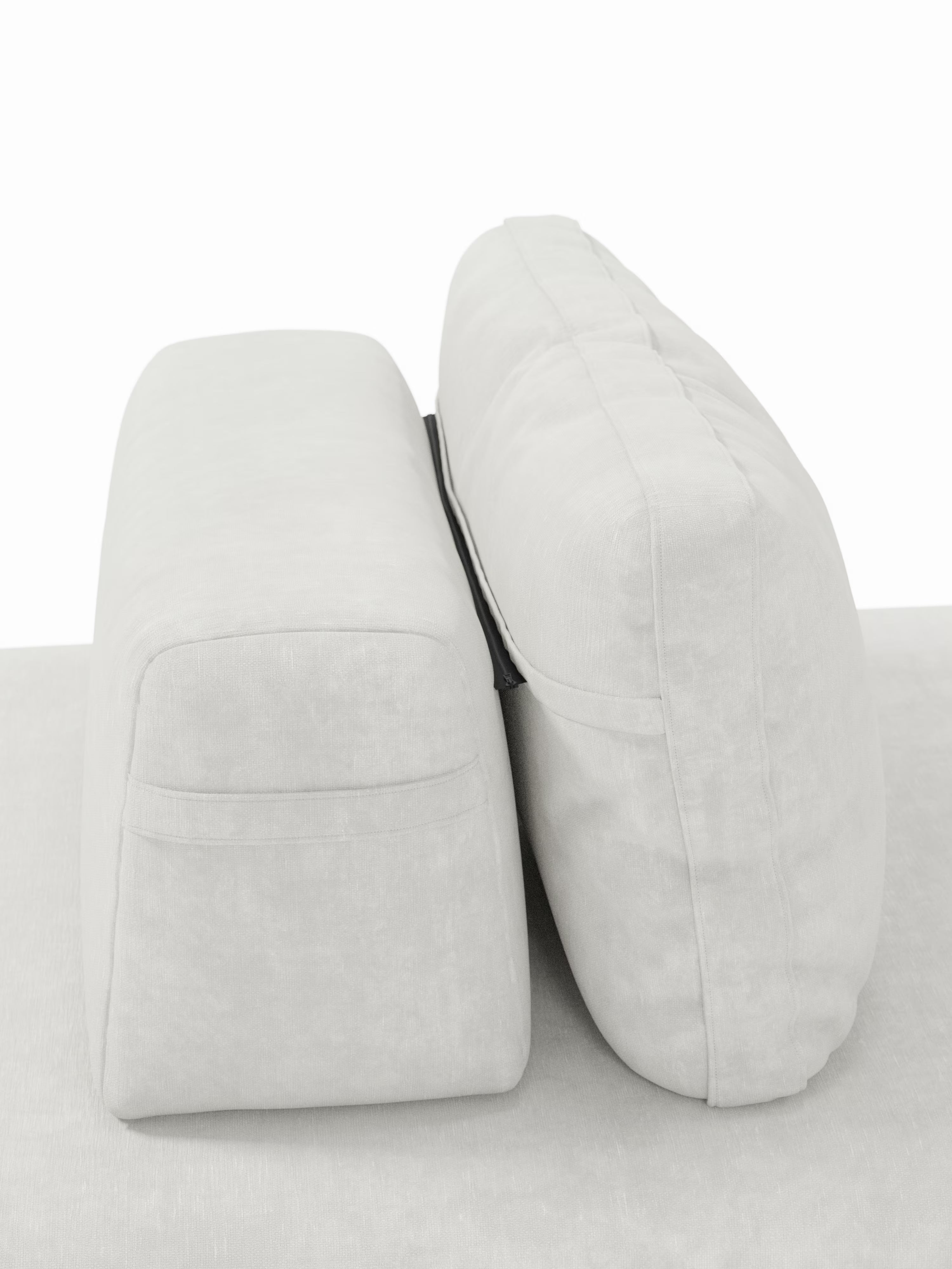 Due schienali rettangolari grigio chiaro della linea Rift, divano letto matrimoniale a 2 e 3 posti con schienali mobili di Divani.Store, sono posizionati in verticale e affiancati su una superficie rivestita in tessuto coordinato. Uniti al centro da una fascia nera, mettono in risalto il loro notevole spessore e la morbida e soffice imbottitura in schiuma memory T31 con un materasso alto 22 cm, evocando il comfort tipico dei divani letto contemporanei. Lo sfondo rimane semplice e ordinato.