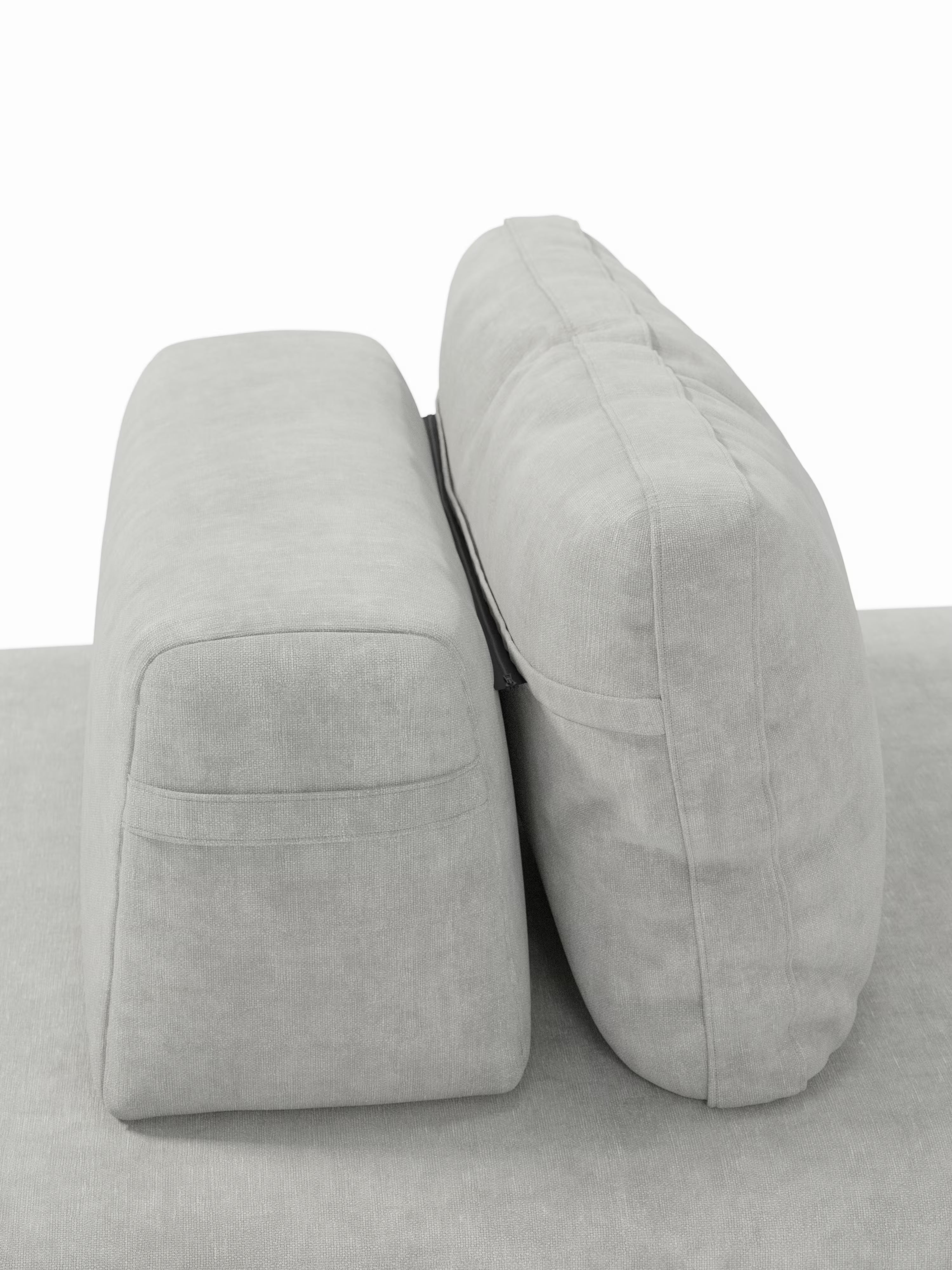 Due cuscini rettangolari grigio chiaro della linea Rift, divano letto matrimoniale a 2 e 3 posti di Divani.Store, sono disposti in posizione verticale uno accanto all’altro. Il cuscino di sinistra appare rigido e squadrato, mentre quello di destra è più morbido e arrotondato, con cuciture a vista. Entrambi poggiano su una superficie in tessuto grigio abbinato, che mette in risalto il design contemporaneo di questo divano letto con schienali orientabili e un materasso in memory foam T31 alto 22 cm.