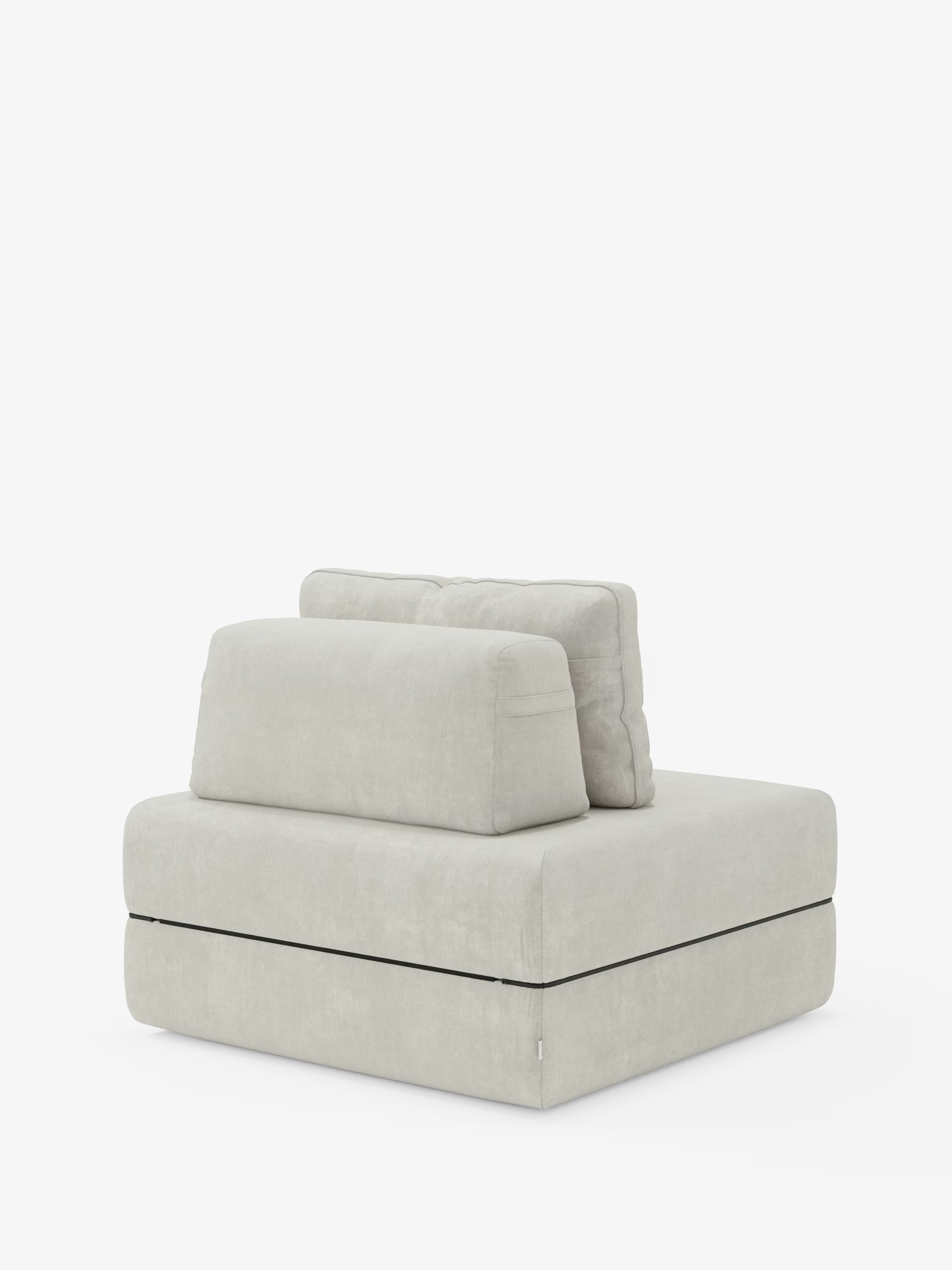 Ecco una frase riscritta utilizzando i dati del prodotto forniti: La poltrona letto Rift con materasso alto 24 cm e memory foam di Divani.Il modello presenta un design moderno senza braccioli, realizzato in tessuto T31 smacchiabile grigio chiaro, con seduta squadrata, cuscino dello schienale rettangolare mobile e cuscino lombare coordinato, il tutto poggiato su una base spessa e bassa rifinita con bordino nero, che offre un'elegante soluzione di poltrona letto presentata su uno sfondo bianco a tinta unita.
