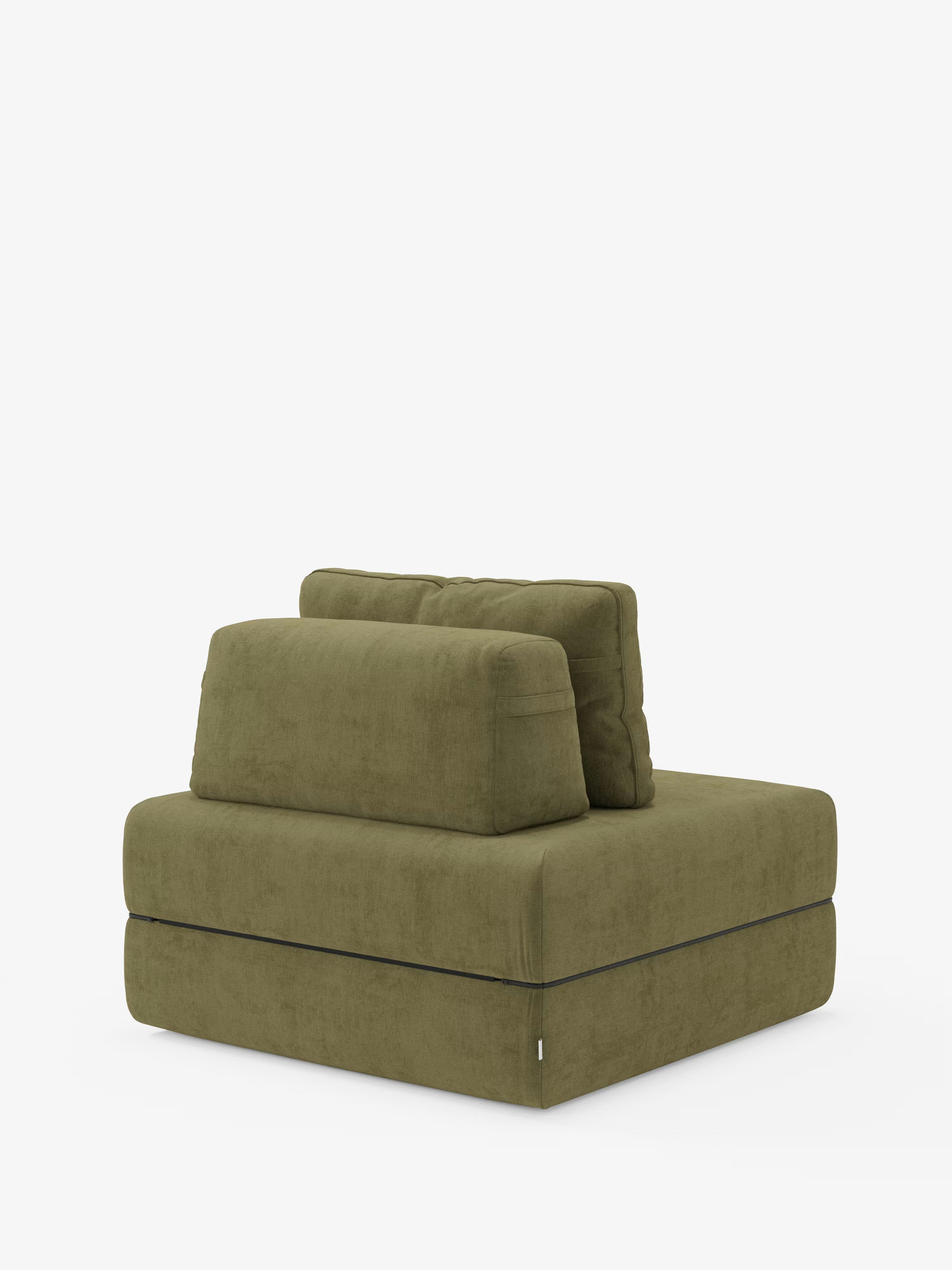 La poltrona letto Rift di Divani.Store è una poltrona senza braccioli di colore verde oliva, caratterizzata da un design squadrato e moderno con seduta rettangolare e due cuscini dello schienale sovrapposti. Rivestita in morbido tessuto T31 resistente alle macchie, presenta uno schienale mobile per un maggiore comfort ed è dotata di un materasso in memory foam alto 24 cm. I dettagli minimalisti risaltano sullo sfondo bianco a tinta unita.