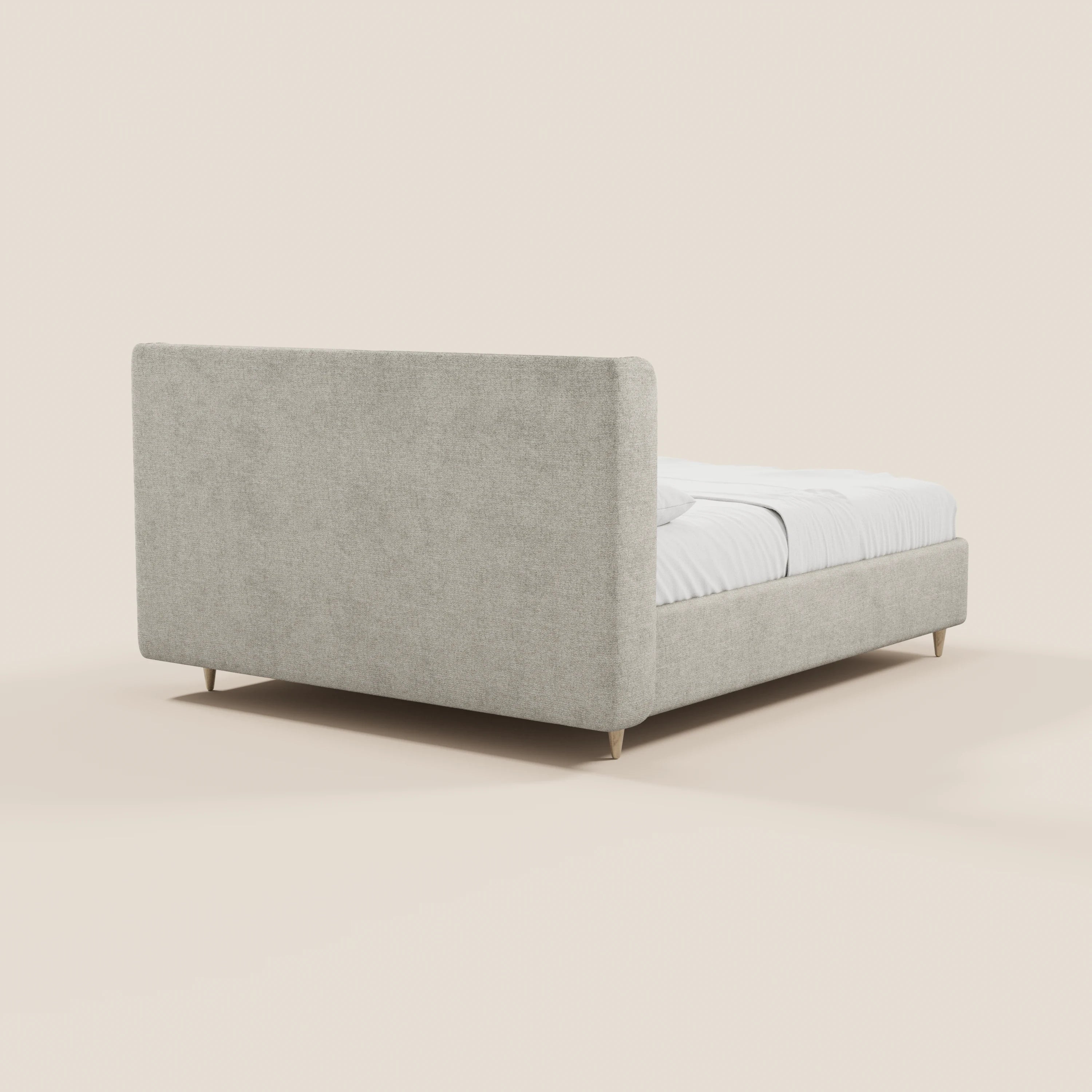 Il letto imbottito bicolore VALKIRIA di Letti.store presenta una testiera curva e imbottita con vano portaoggetti, due cuscini per lo schienale e semplici gambe in legno. Nell’immagine è raffigurato con biancheria da letto e cuscini bianchi, visto da dietro a sinistra su uno sfondo neutro.