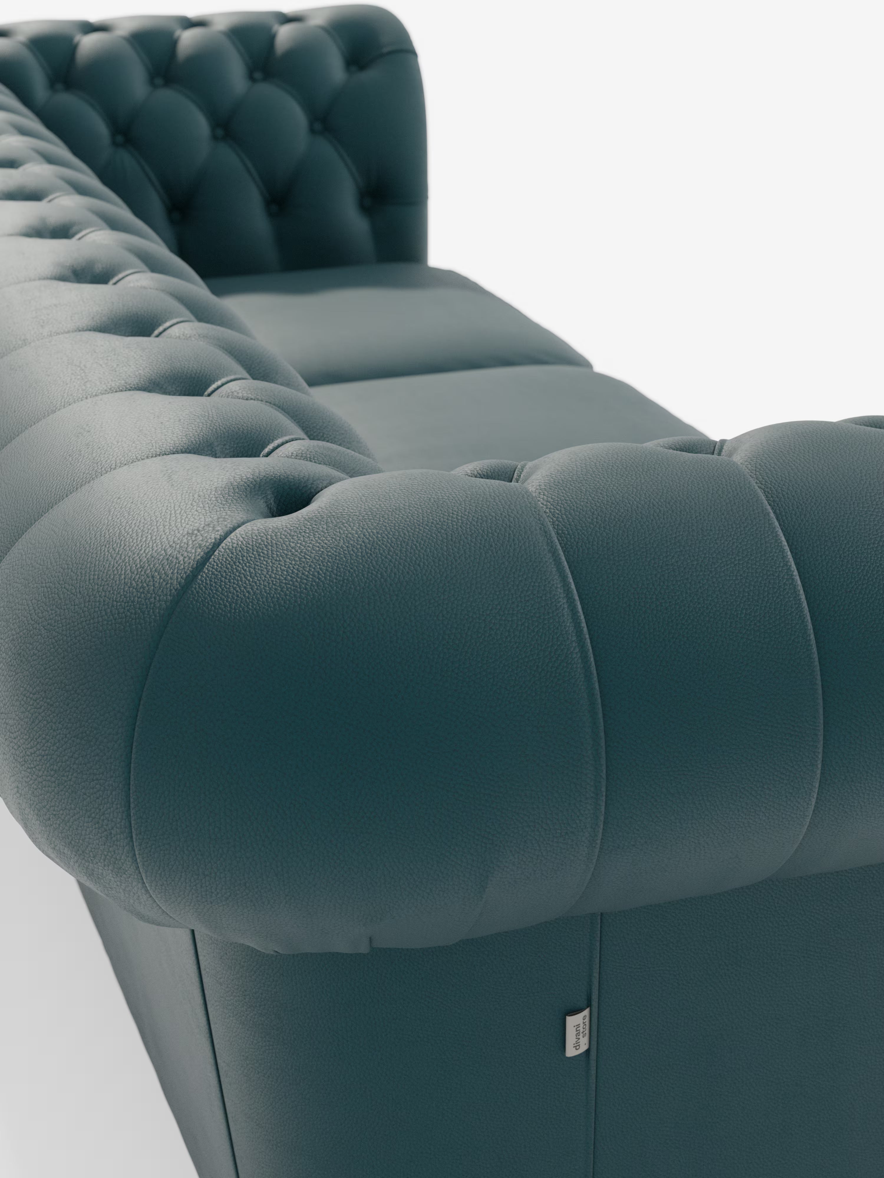 Primo piano del Chester 4 Posti 3 sedute in Vera Pelle – Chesterfield Capitonné Artigianale di Divani.Store, un divano in pelle color verde acqua scuro con finitura capitonné, caratterizzato da profondi bottoni decorativi e morbidi braccioli arrotondati. Realizzato con maestria in vera pelle di prima qualità e ispirato al classico stile Chesterfield, il divano mette in risalto la ricca trama della pelle. Una piccola etichetta in tessuto è applicata vicino alla base, su uno sfondo bianco a tinta unita.