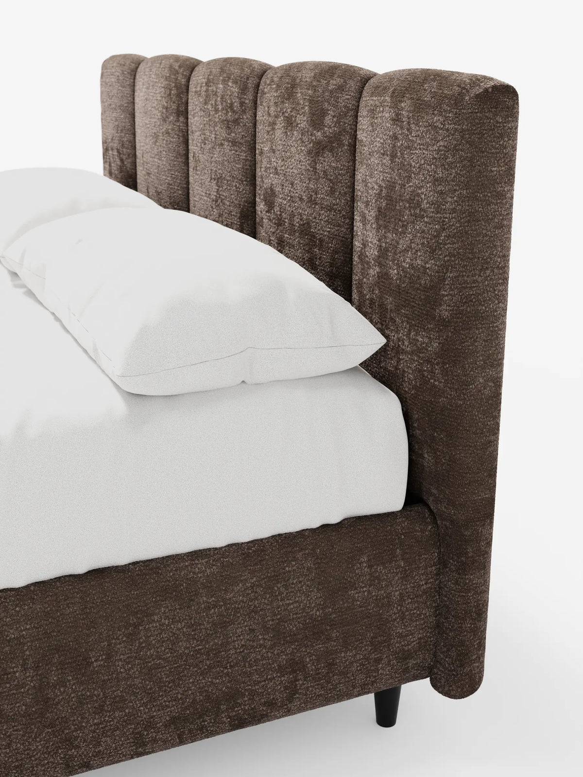 Un primo piano del letto imbottito ARKAM con contenitore e testiera a lavorazione verticale in tessuto testurizzato marrone scuro, caratterizzato da una testiera trapuntata a canali su sfondo bianco con biancheria da letto di un bianco brillante.