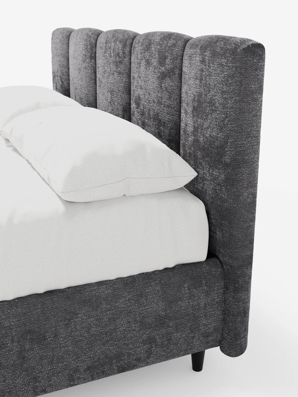 Il letto imbottito ARKAM con contenitore e testiera a cuciture verticali è un letto imbottito in tessuto grigio scuro a trama ruvida, con testiera a cuciture verticali, piccole gambe cilindriche e biancheria da letto bianca su uno sfondo a tinta unita.