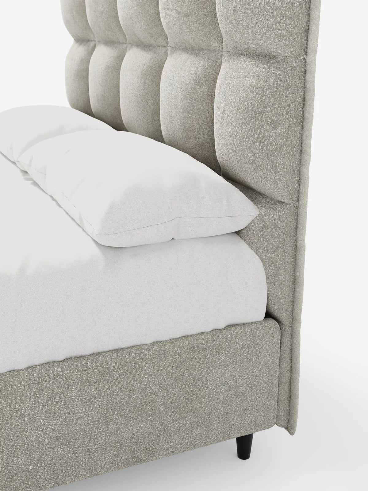 Un primo piano di un letto imbottito AURO con contenitore e testiera alta capitonné in ciniglia Oeko-Tex®, con testiera alta capitonné beige e biancheria da letto bianca, appoggiato su piccole gambe nere su uno sfondo bianco.