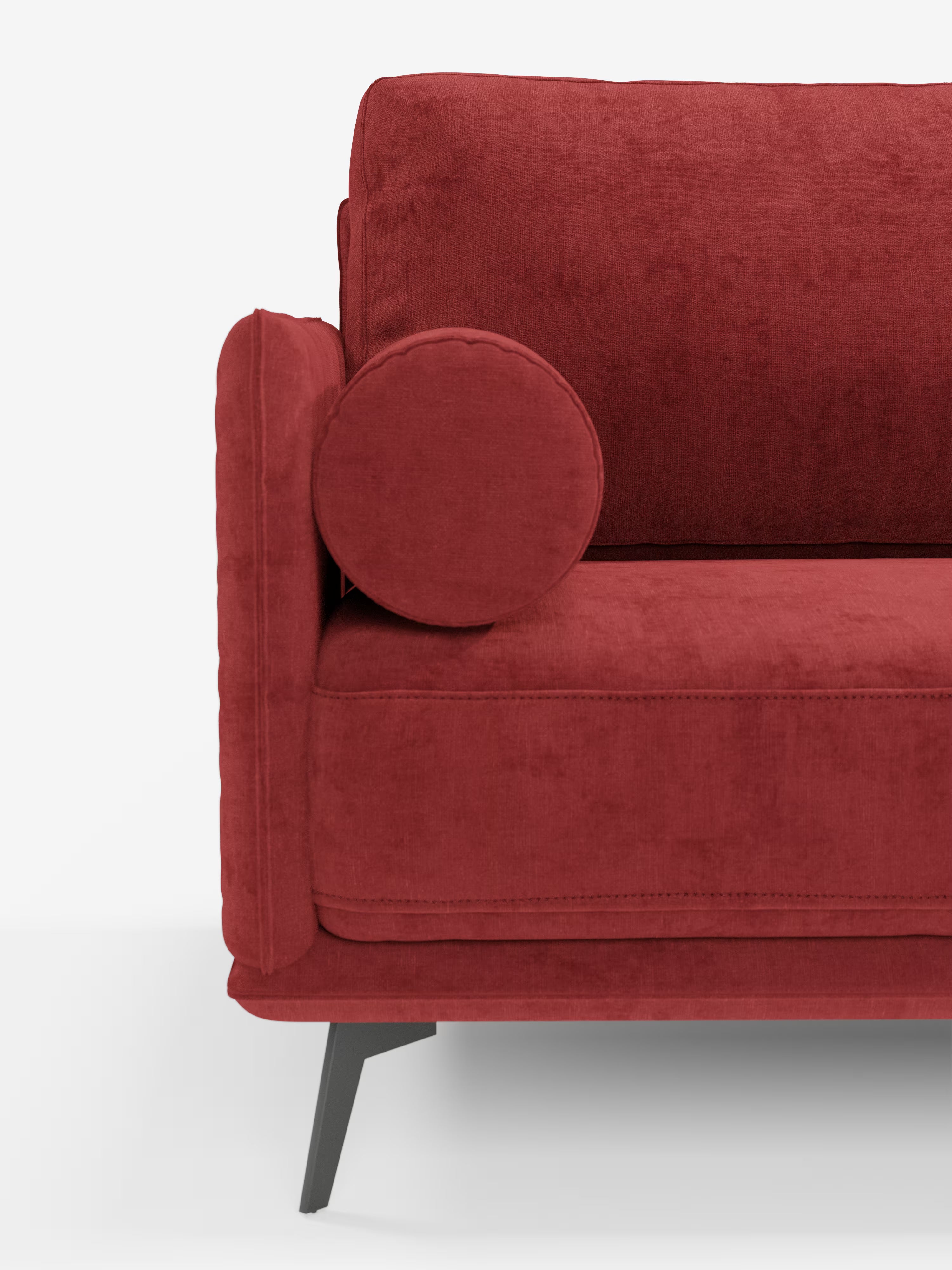 Una vista laterale ravvicinata del divano moderno angolare con penisola “Basalto” di Divani.Store, rivestito in tessuto T31 di un rosso intenso e resistente alle macchie, impreziosito da un cuscino rotondo sul bracciolo, da eleganti gambe angolari in metallo nero e da morbidi cuscini imbottiti di piume, il tutto su uno sfondo bianco a tinta unita.