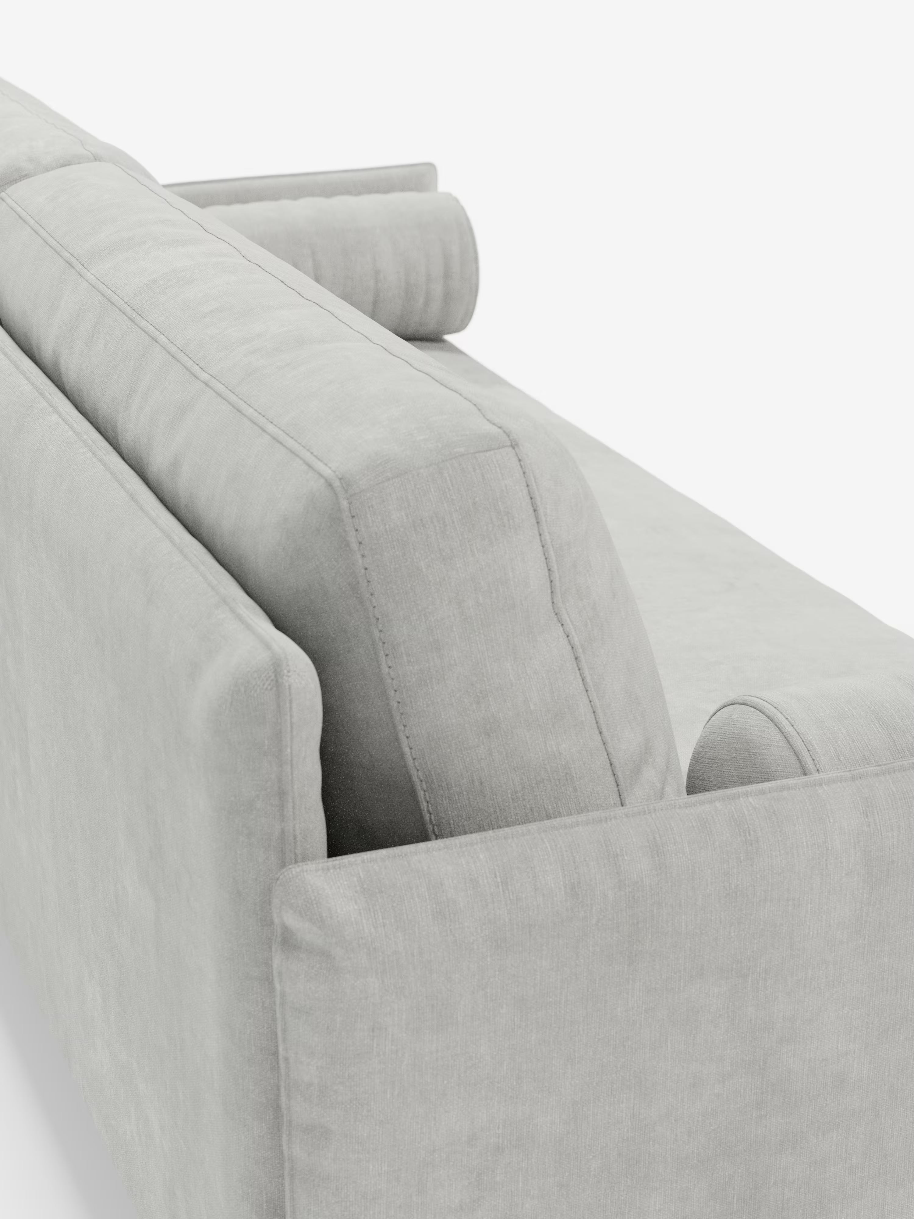 Una vista ravvicinata del retro e del profilo della moderna linea “Basalto Divano lineare 2 o 3 posti” di Divani.Store, in grigio chiaro, che mette in risalto lo schienale strutturato, il cuscino di seduta singolo e il cuscino cilindrico abbinato, realizzati in tessuto smacchiabile T31 con base in metallo, il tutto su uno sfondo bianco.