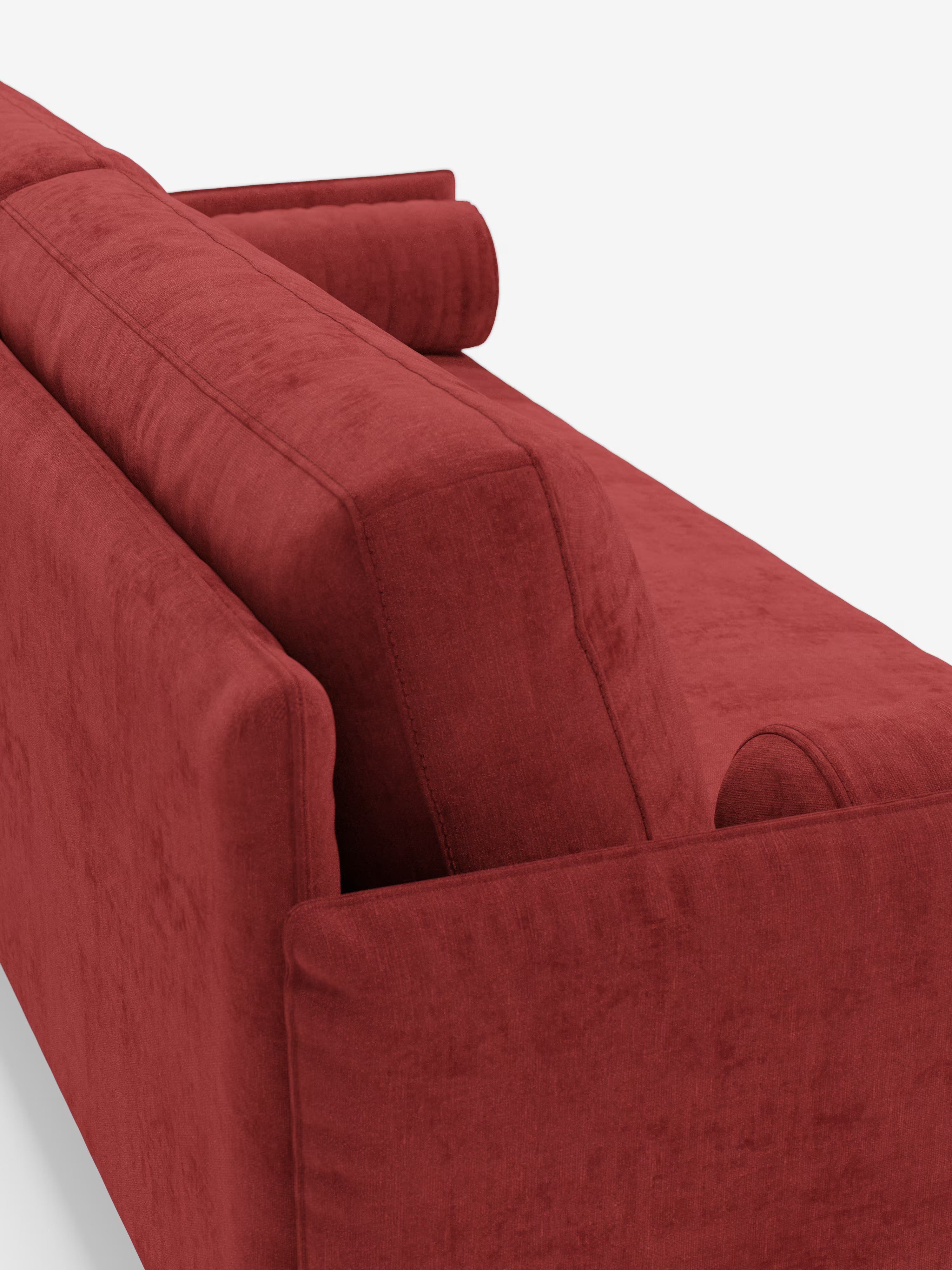 Un primo piano del retro e del profilo del divano Basalto Divano lineare a 2 o 3 posti con seduta unica e base in metallo, rivestito in tessuto antimacchia T31 di Divani.Store, caratterizzato da morbidi cuscini e da un cuscino cilindrico in una vivace tonalità di rosso, che risalta sullo sfondo bianco. Il tessuto antimacchia appare morbido e presenta una superficie testurizzata, che mette in risalto il design elegante e contemporaneo del divano.