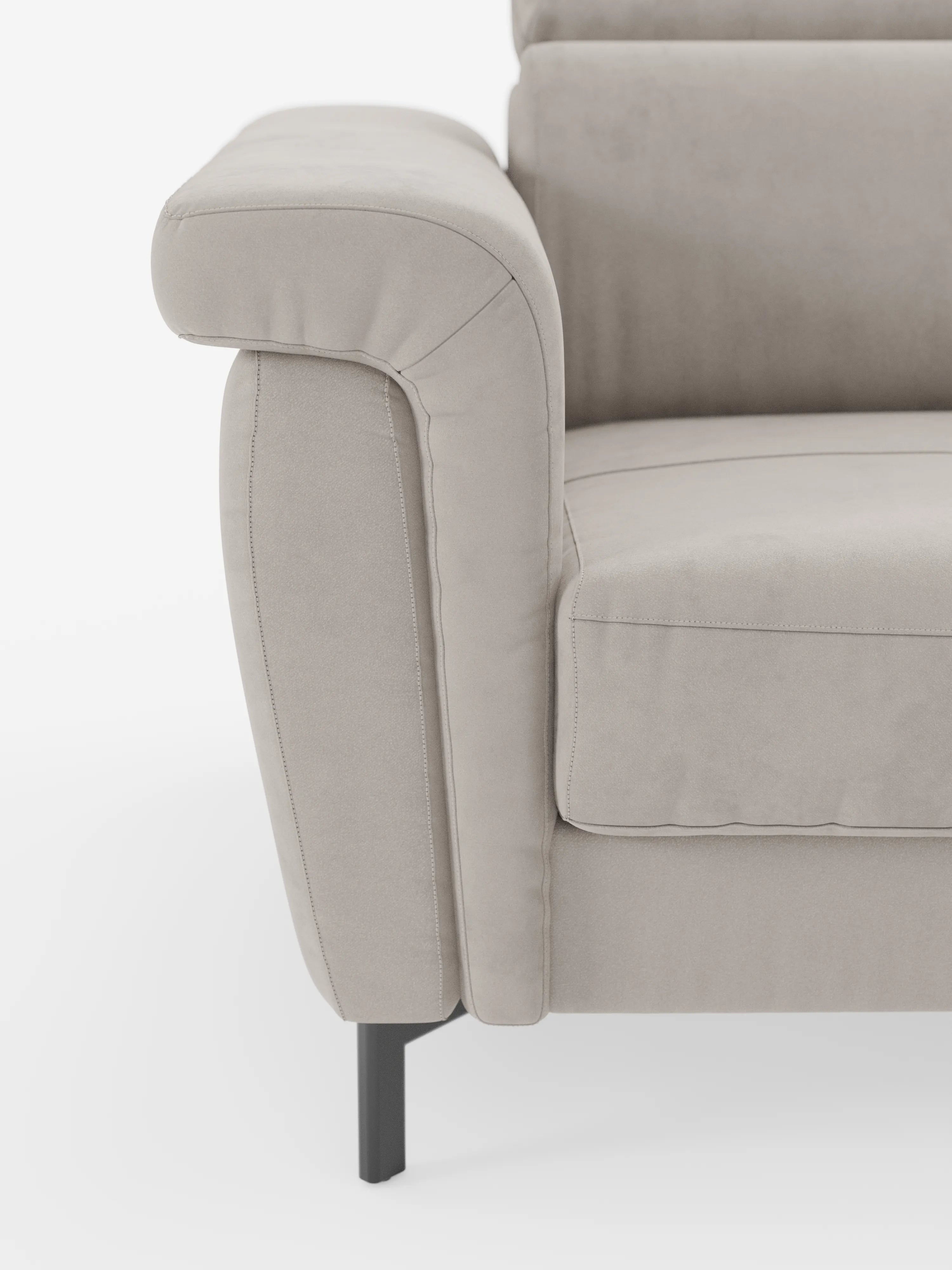 Primo piano del bracciolo sinistro e del cuscino di seduta del divano letto di design Capri con piedini alti di Divani.Store, rivestito in un raffinato tessuto effetto velluto smacchiabile T30, morbido al tatto. Questo divano beige presenta linee pulite, cuciture a vista e poggia su eleganti gambe in metallo nero con poggiatesta regolabili: un esempio straordinario di manifattura italiana. Lo sfondo è bianco a tinta unita.