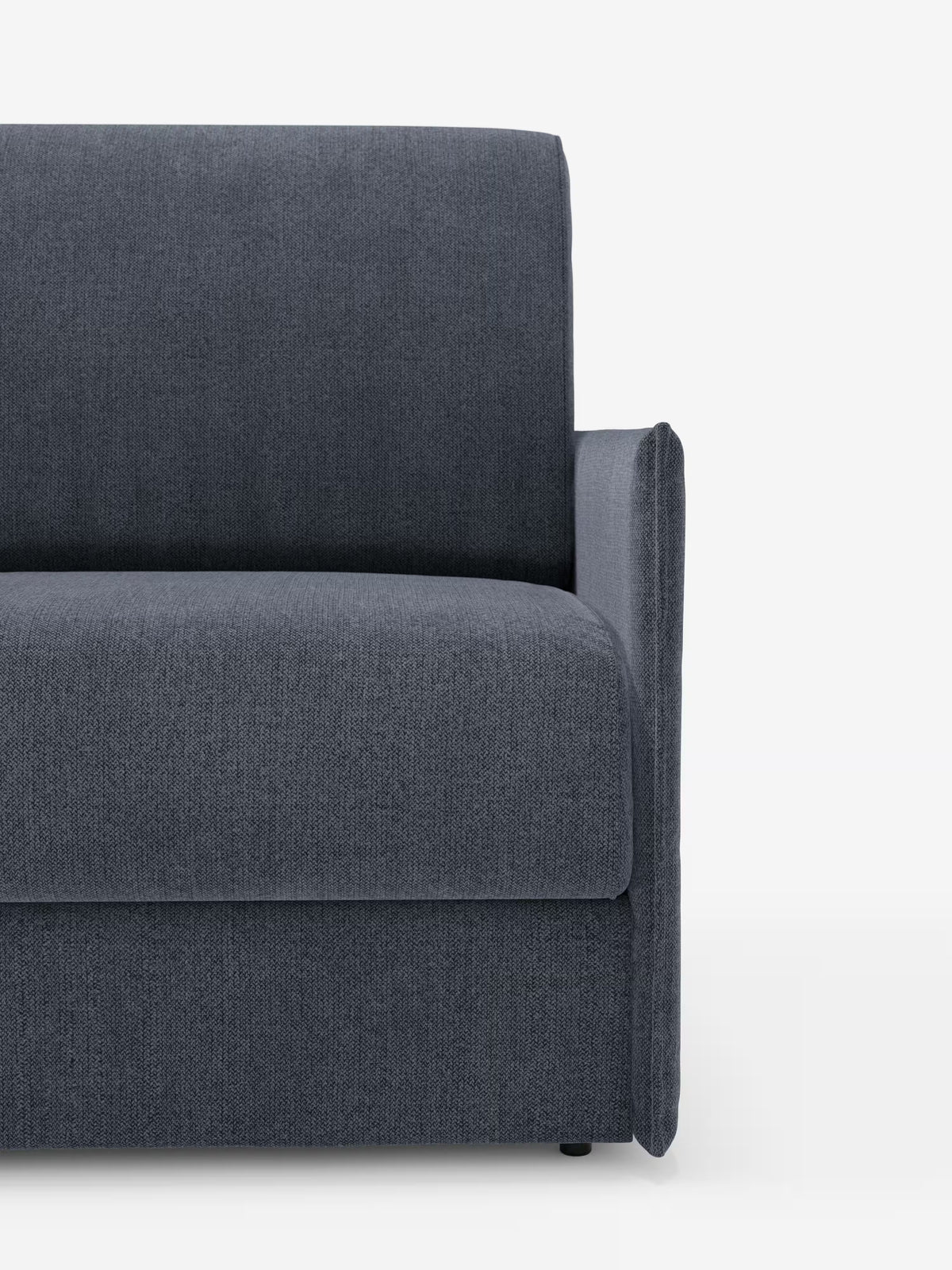 Un primo piano della metà destra della poltrona letto compatta Evans con materasso di Divani.Store ne mette in risalto il rivestimento moderno in grigio scuro, realizzato in tessuto sfoderabile e antimacchia T23, caratterizzato da braccioli e schienale bassi e squadrati. Questo versatile complemento d’arredo funge sia da elegante divano che da pratica poltrona letto singola, rendendolo un’eccellente soluzione salvaspazio per qualsiasi zona giorno contemporanea. La trama del tessuto risalta sullo sfondo