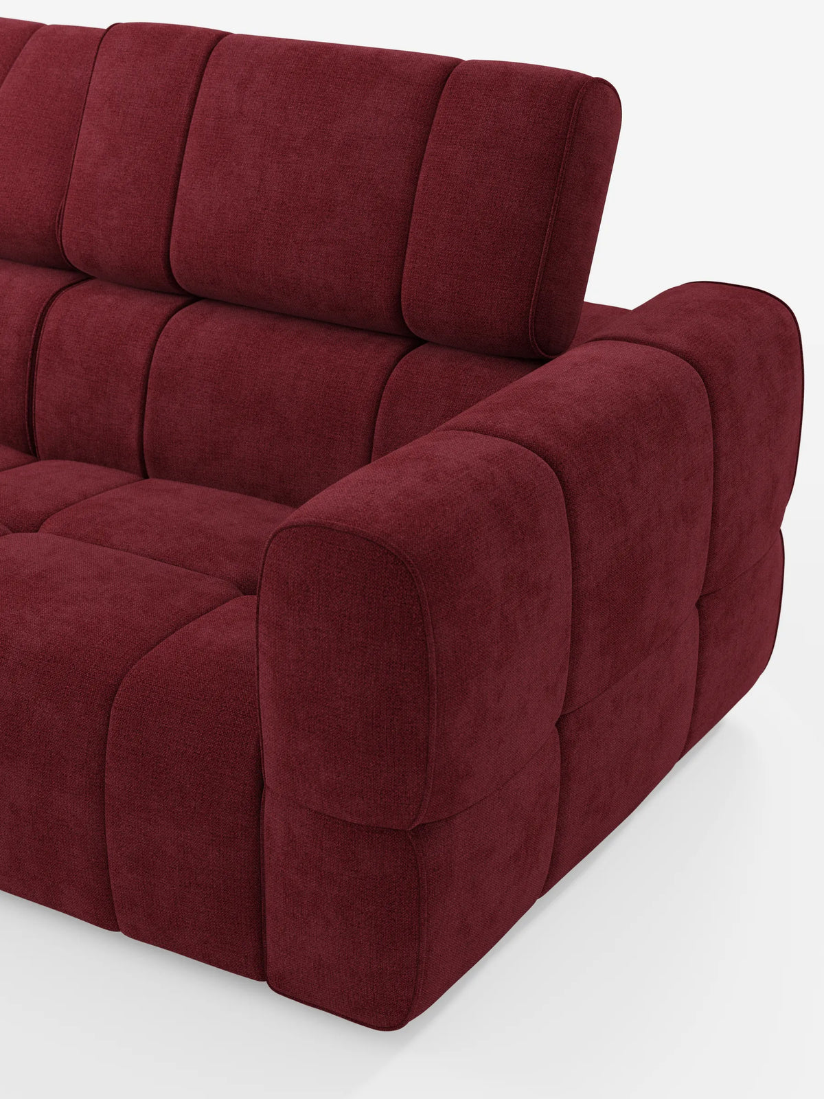 Un divano componibile Giotto di colore rosso intenso con terminale aperto – opzione relax elettrico in tessuto smacchiabile T23, con finitura a pannelli testurizzata, cuscini spessi e arrotondati e poggiatesta regolabile su sfondo bianco.