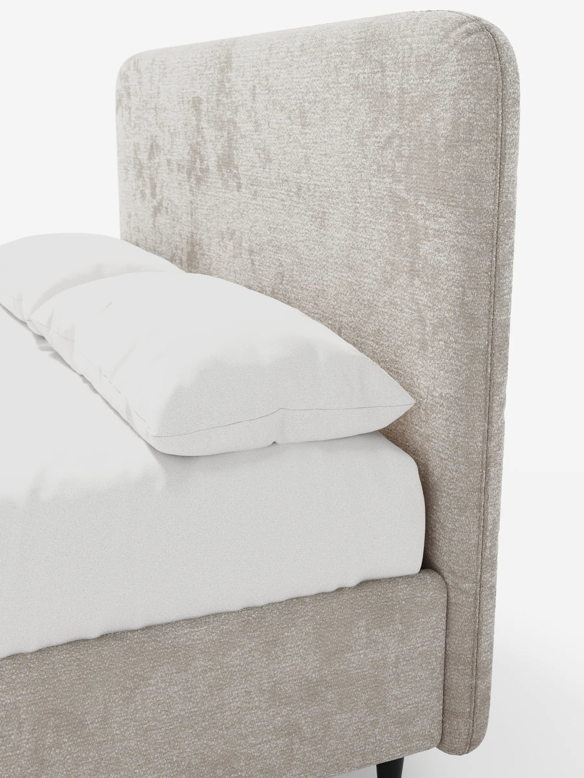 Profilo laterale di un letto KAELOS minimal imbottito con testiera arrotondata in tessuto beige testurizzato, rivestito con lenzuola bianche, su gambe scure e slanciate, su uno sfondo bianco uniforme.