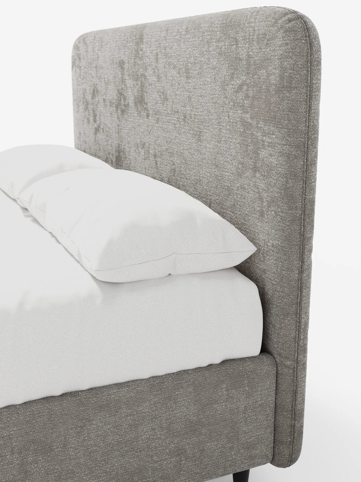 Un primo piano del letto imbottito KAELOS Letto Minimal, con testiera arrotondata e rivestita in tessuto chenille grigio-marrone a trama ruvida, caratterizzato da un cuscino bianco su biancheria da letto liscia, una base contenitiva dal profilo basso e gambe sottili di colore scuro.
