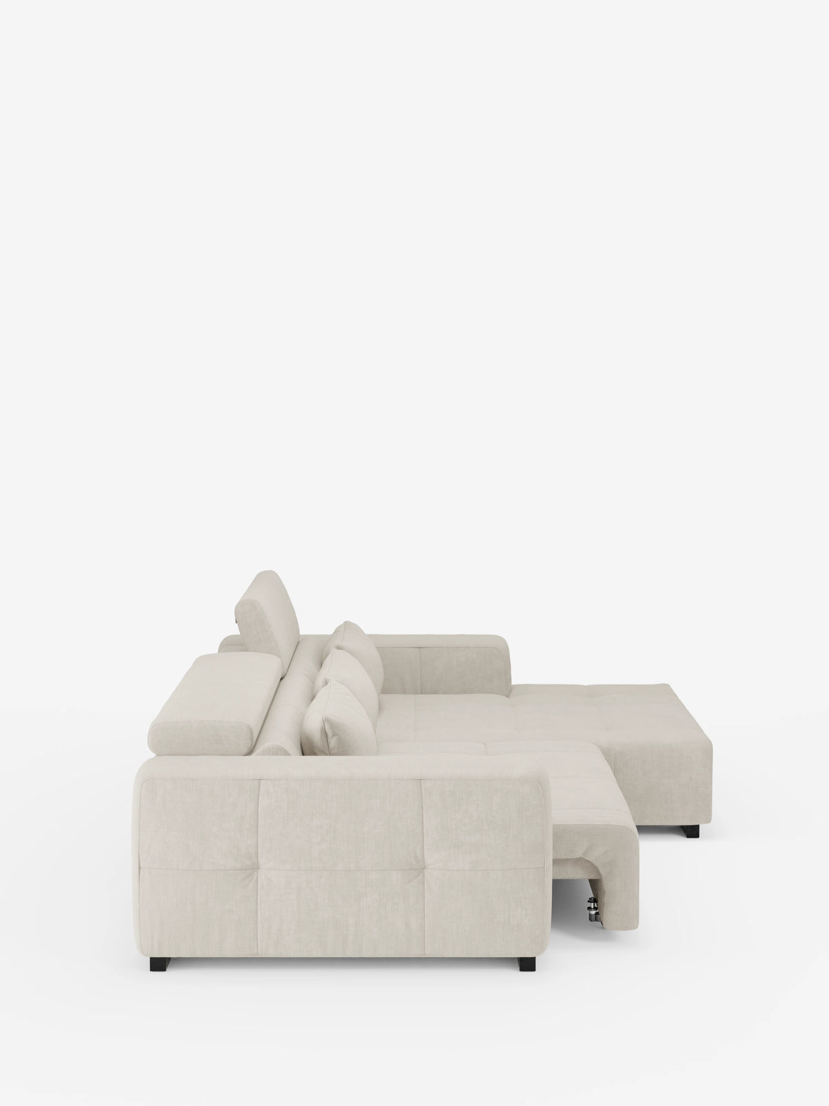 Una vista laterale mostra il divano angolare Monarch con penisola e funzione Relax Elettrico per l’allungamento delle sedute di Divani.Store, caratterizzato da un design moderno in beige chiaro con cuscini di seduta trapuntati e poggiatesta reclinabili regolabili. La sezione chaise allungata e le gambe basse nere risaltano chiaramente sullo sfondo bianco a tinta unita. Rivestito in morbido tessuto T31 resistente alle macchie.