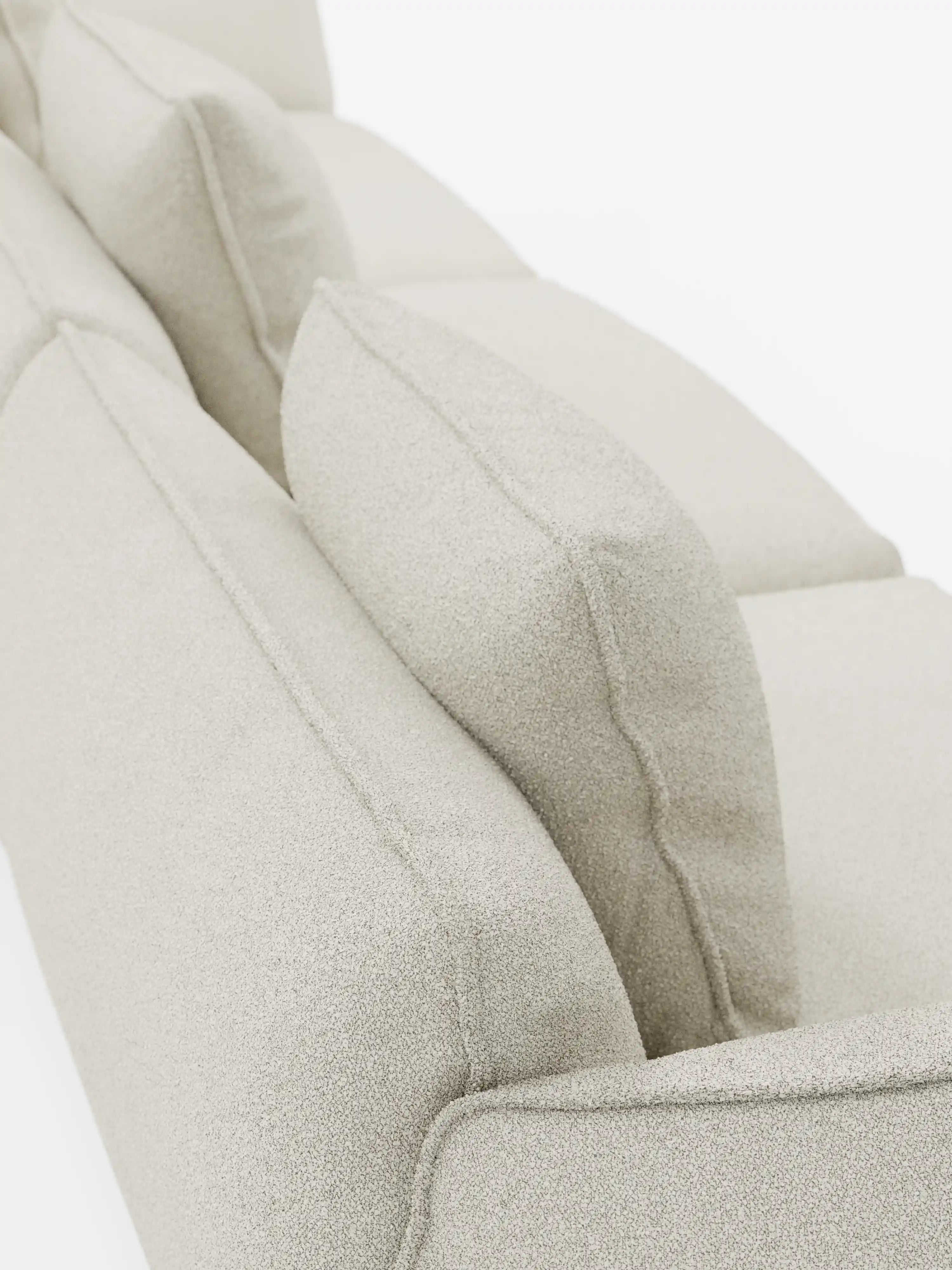 Primo piano del divano modulare a 3 posti “Nimbus” di Divani.Store, presentato in tessuto T33 beige chiaro, testurizzato, smacchiabile, effetto cotone. I cuscini spessi della seduta e dello schienale sono ripresi da una prospettiva angolata e dall’alto, mettendo in risalto le cuciture dettagliate e la struttura del divano modulare su uno sfondo bianco a tinta unita.
