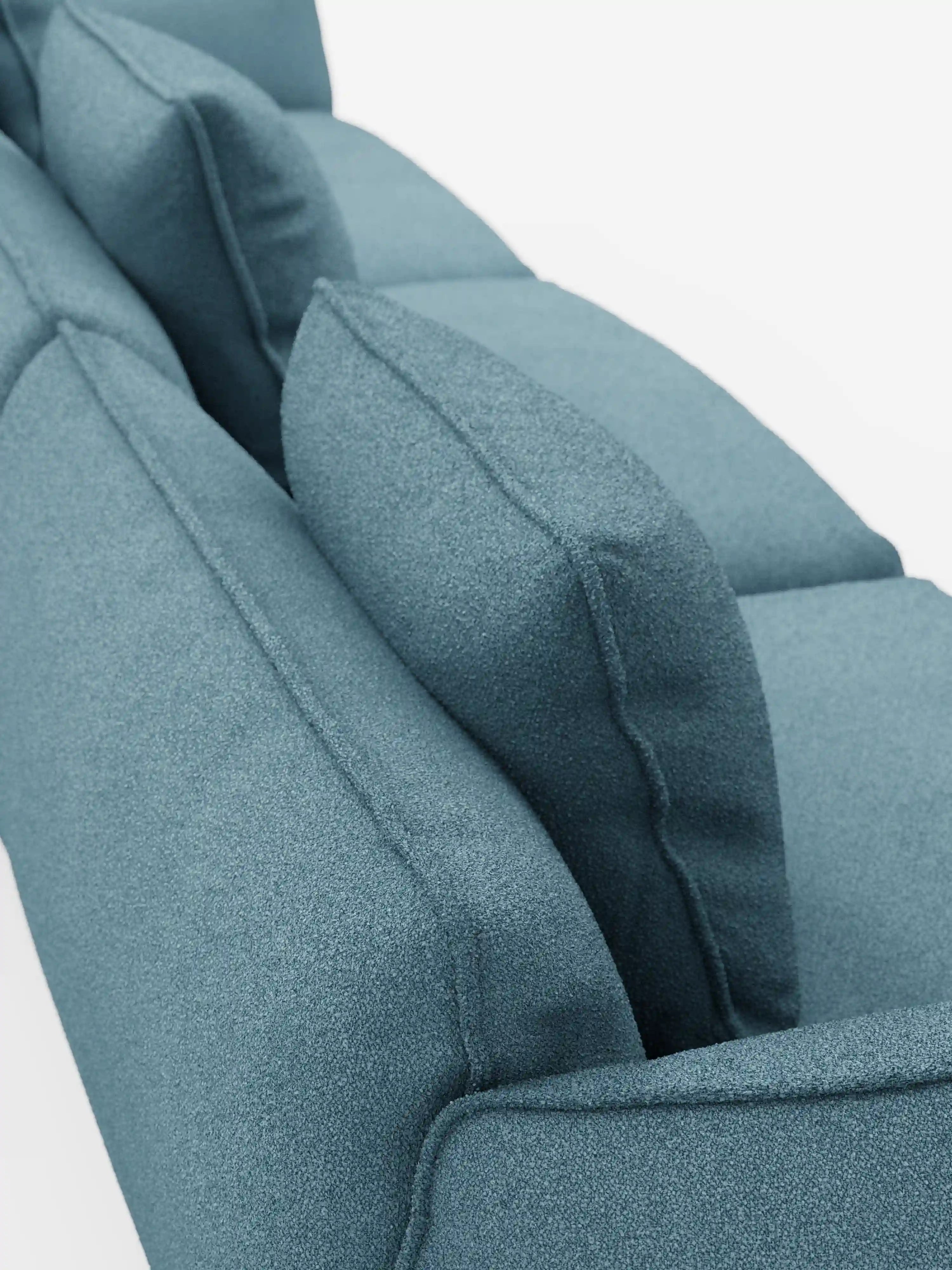 Un primo piano del divano modulare a 3 posti Nimbus, realizzabile in morbido tessuto smacchiabile effetto cotone T33 di Divani.Store, che mette in risalto il rivestimento in tonalità verde acqua con texture, lo schienale e i cuscini angolari dello schienale su uno sfondo bianco. Questo divano moderno è caratterizzato da cuscini eleganti e morbidi che ne sottolineano il design contemporaneo e l’imbottitura confortevole.