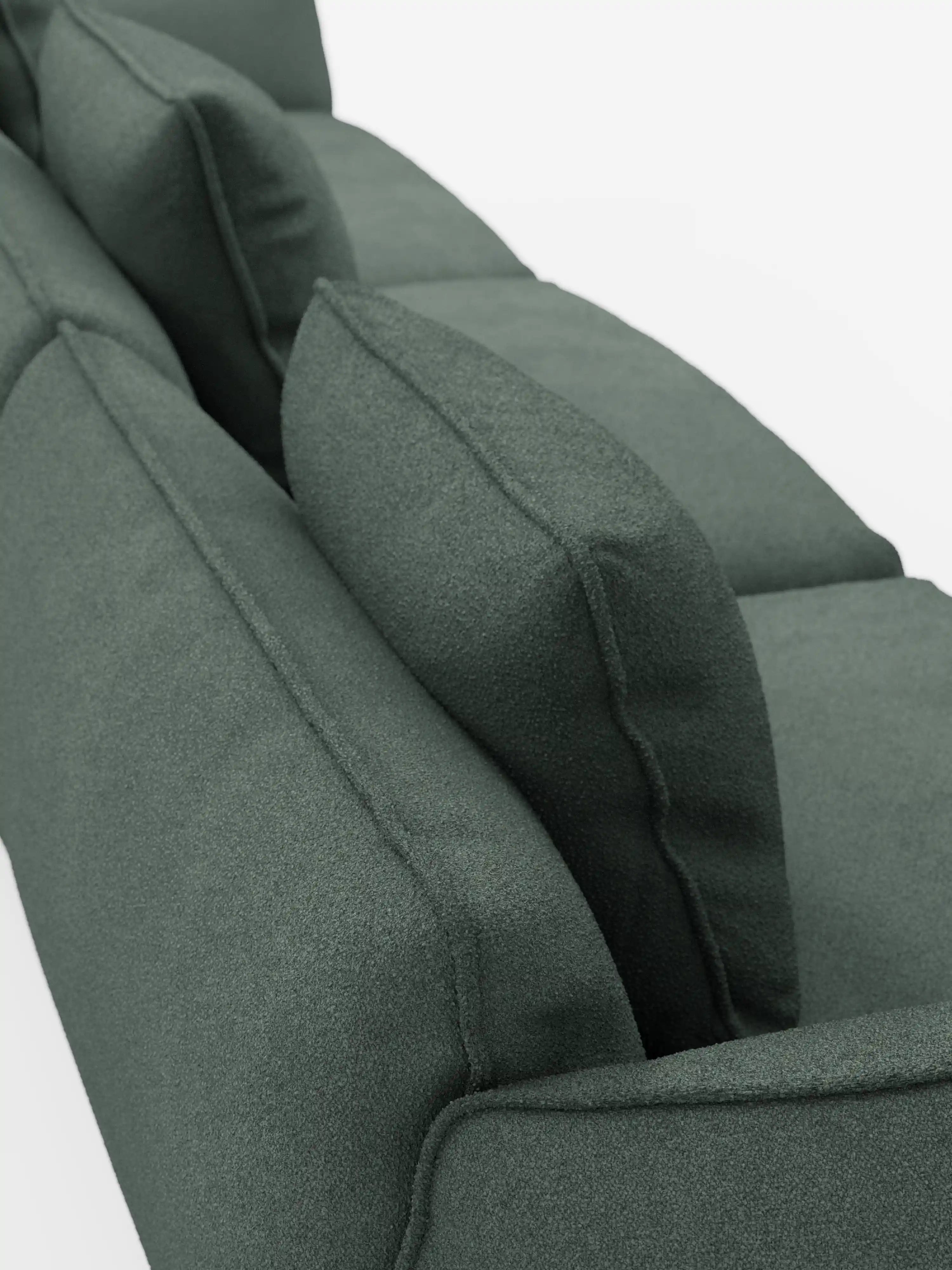 Primo piano del divano modulare a 3 posti Nimbus di Divani.Store, rivestito in tessuto T33 verde scuro smacchiabile effetto cotone. L'immagine, ripresa dall'alto, mette in risalto i cuscini dello schienale e della seduta perfettamente allineati con le cuciture a vista, il tessuto dalla trama morbida e l'imbottitura spessa su uno sfondo bianco.